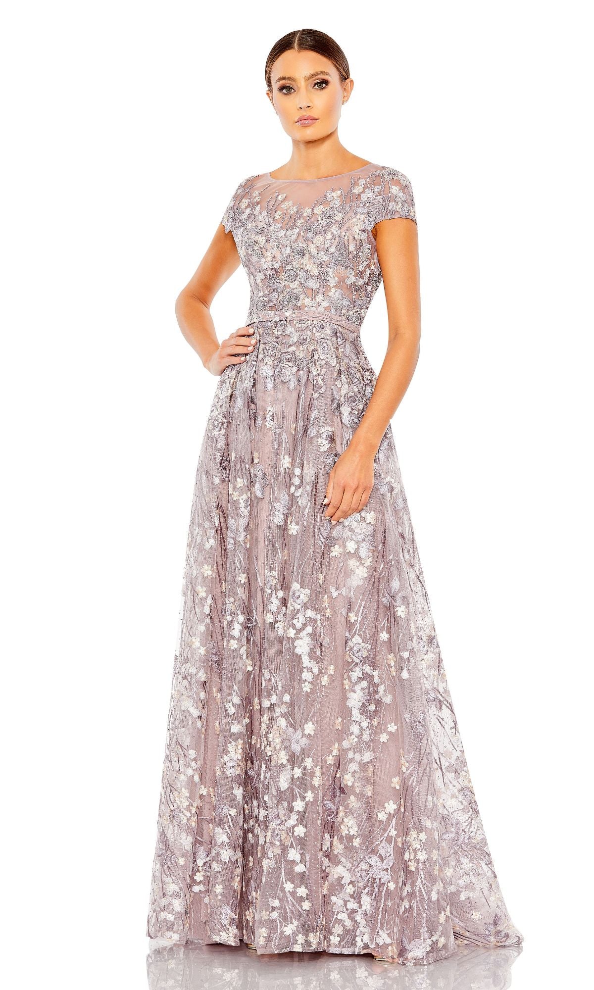 A woman poses against a white background wearing the Mac Duggal 20405 Short-Sleeve Long Formal Dress in lavender, featuring floral embroidery and a sheer neckline.
