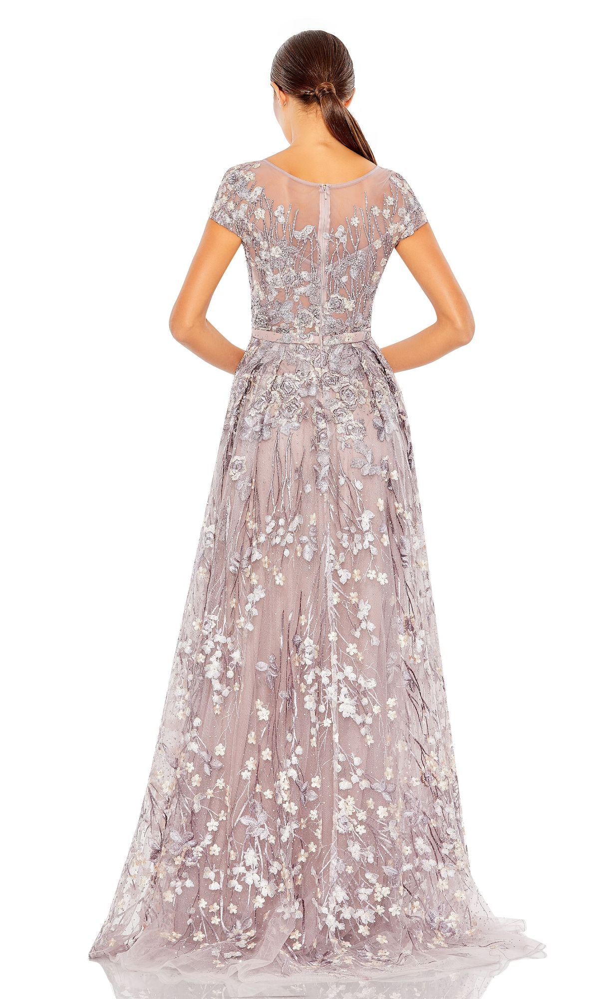 A woman faces away from the camera in a floor-length Mac Duggal 20405 Short-Sleeve Long Formal Dress in lavender, featuring intricate floral embroidery and a sheer upper back—an ideal embroidered-lace evening gown for special occasions.