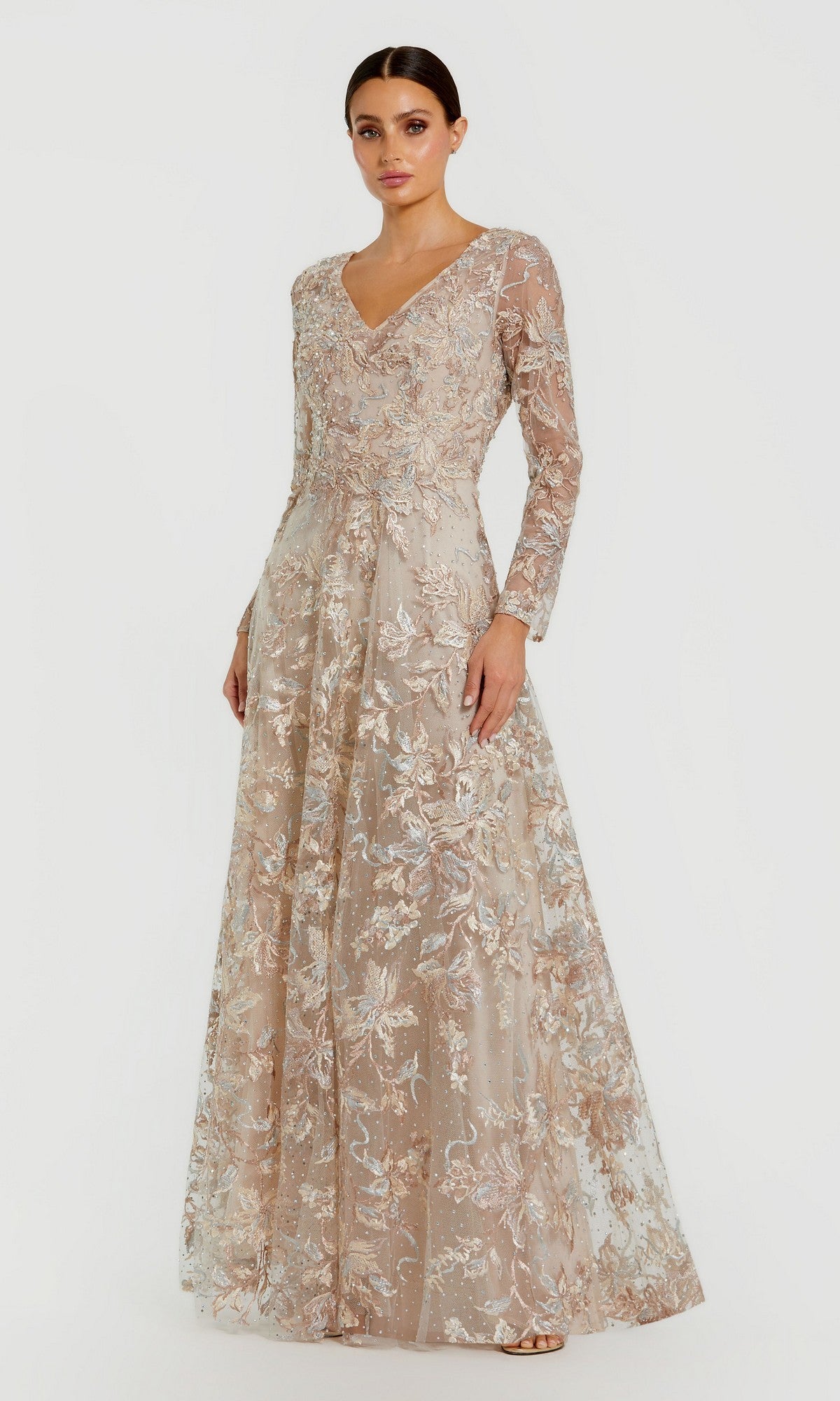 A woman stands against a plain white background wearing the Mac Duggal 20409 long formal dress in champagne, featuring lace embroidery, an A-line silhouette, long sleeves, and a V-neckline.