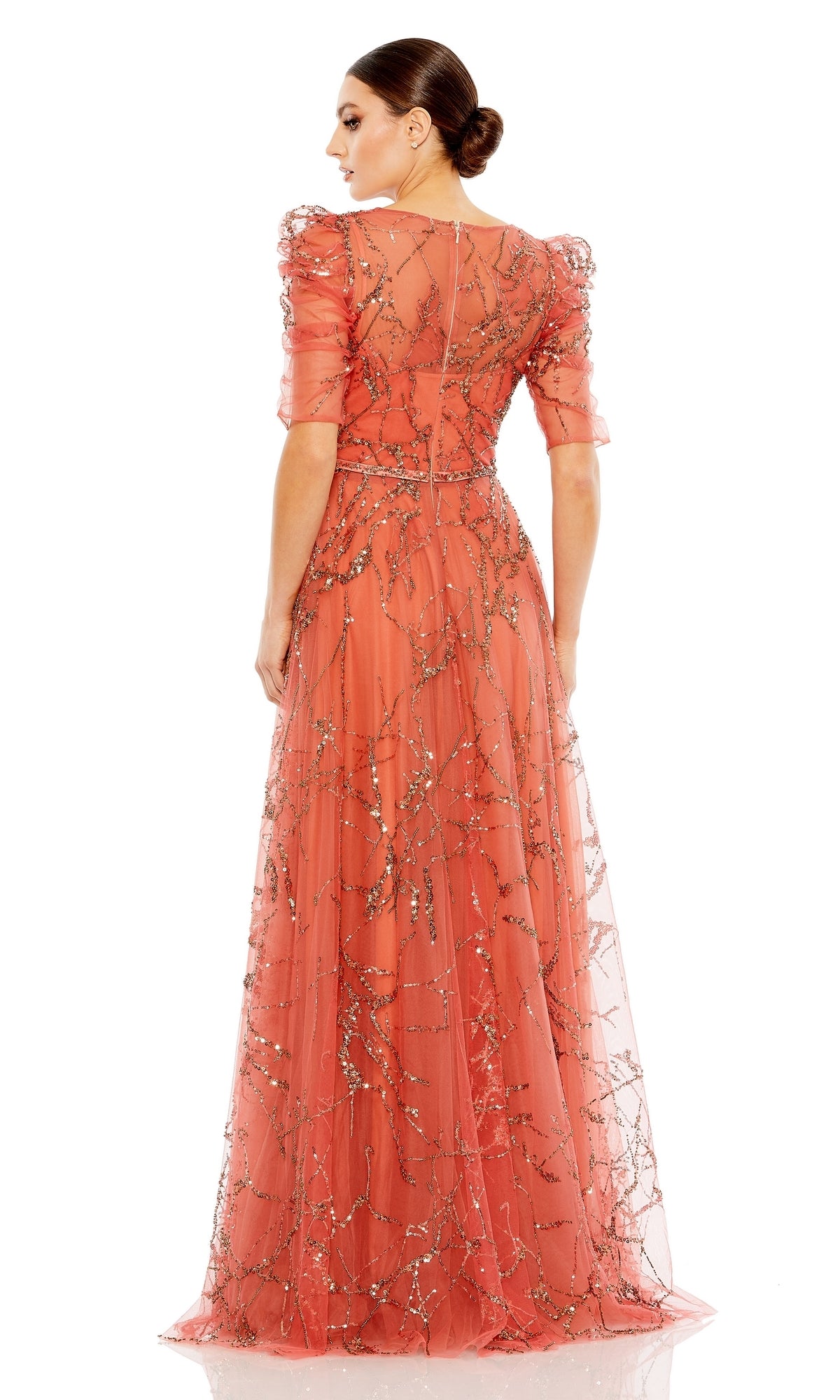 Woman with back to camera in the Long Formal Dress 20428 by Mac Duggal—a floor-length coral A-line gown featuring sheer sleeves, a V-neckline, and metallic embroidered patterns.