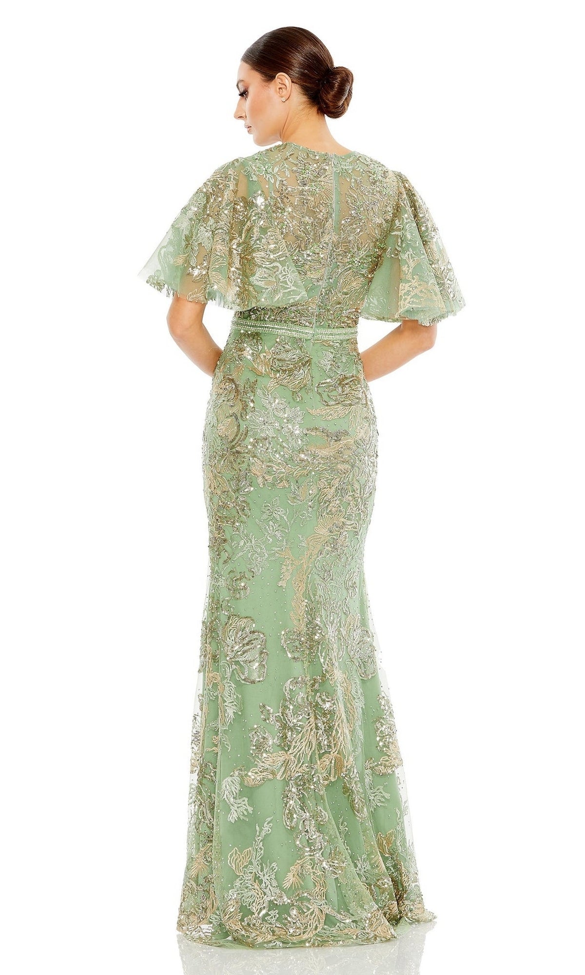 A woman faces away in the Mac Duggal 20438 Flutter-Sleeve Lace Formal Dress—floor-length, sage green, with gold floral embroidery and flutter sleeves—her low bun accentuates the sparkling embroidered lace.