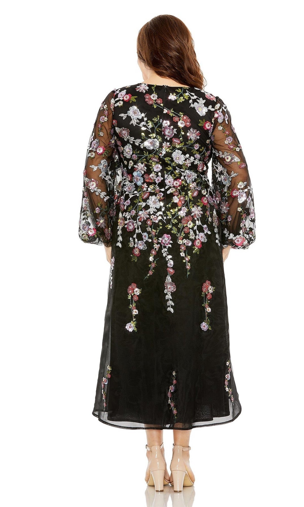 A woman faces away, wearing the Plus-Size Semi-Formal Dress 20474 by Mac Duggal—a black sheer long-sleeve midi dress with colorful floral embroidery—paired with nude heels.