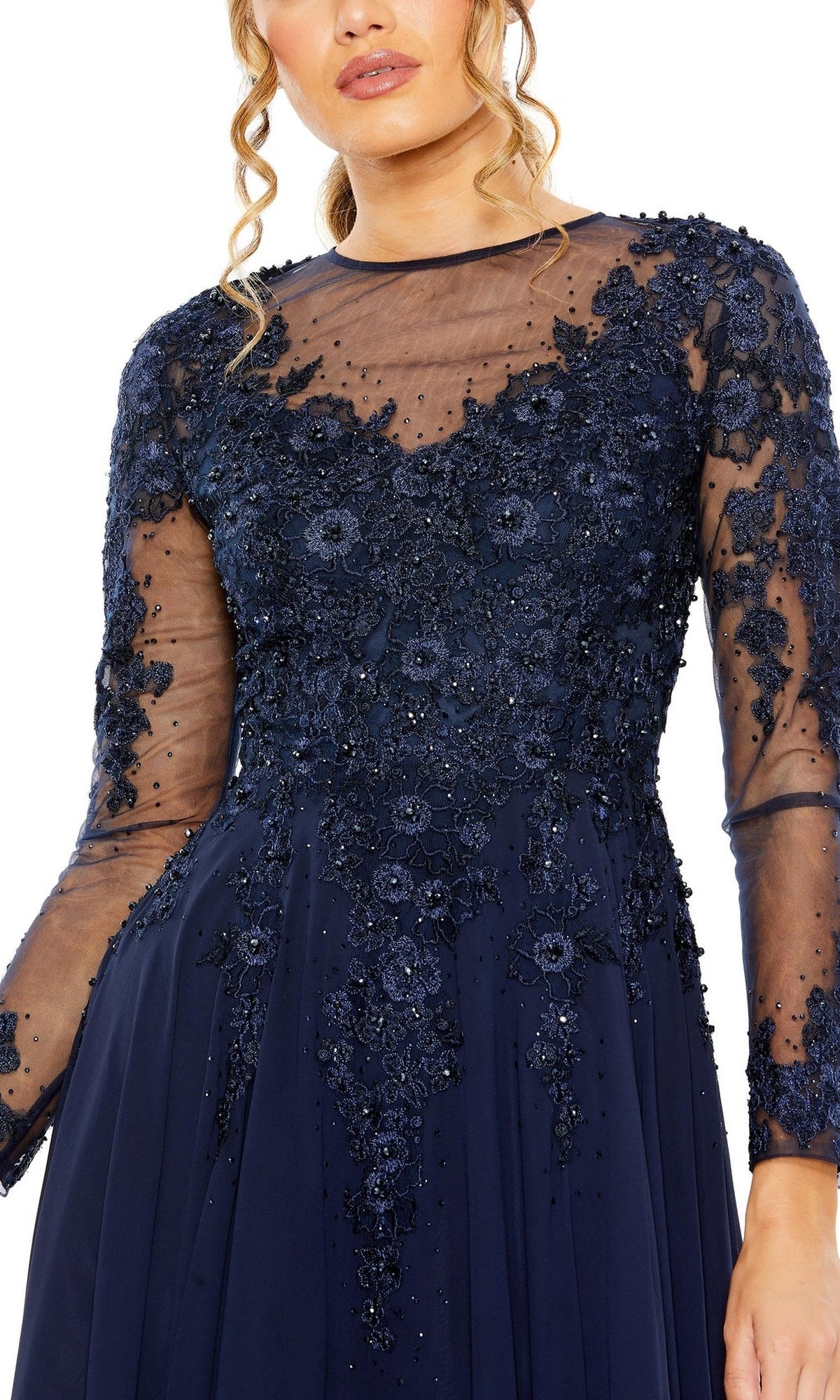 A woman wearing the Mac Duggal 20478 long sleeve formal dress featuring navy blue sheer mesh sleeves and intricate bead and floral lace embellishments, perfect as a mother of the bride gown.