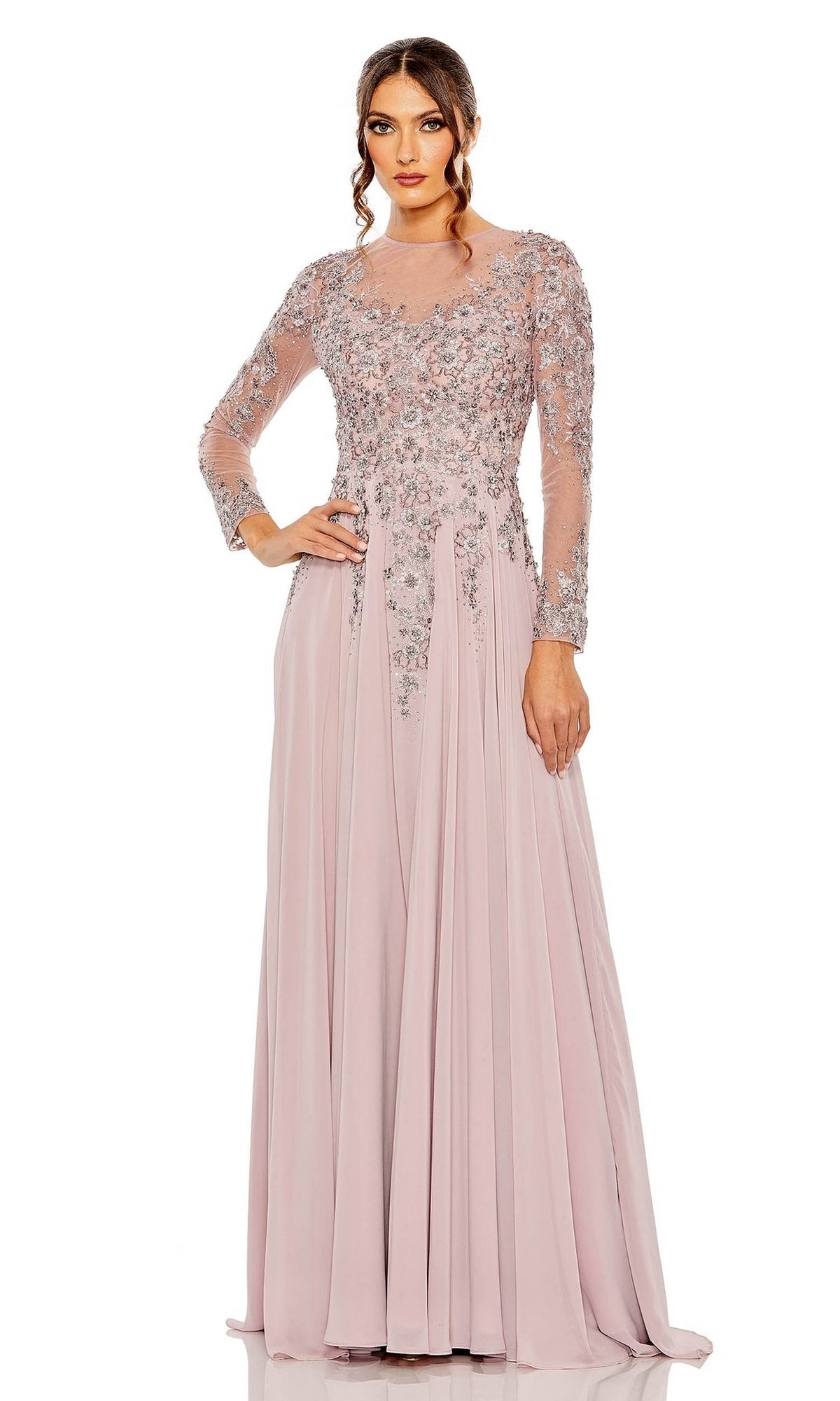 A woman models the Mac Duggal 20478 long sleeve formal dress—a light pink A-line gown with sheer sleeves and floral embroidery on the bodice—against a plain white background.