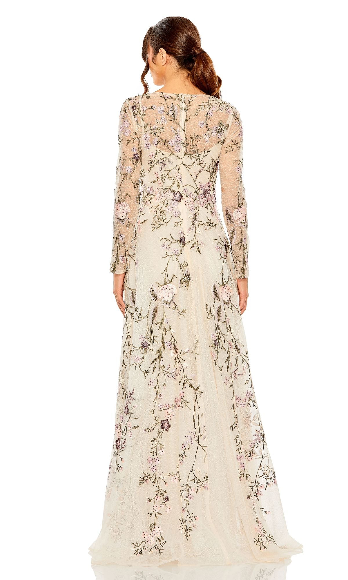 A woman with brown hair in a low ponytail faces away, wearing the Mac Duggal 20480 long sleeve pink evening gown featuring floral embroidery.