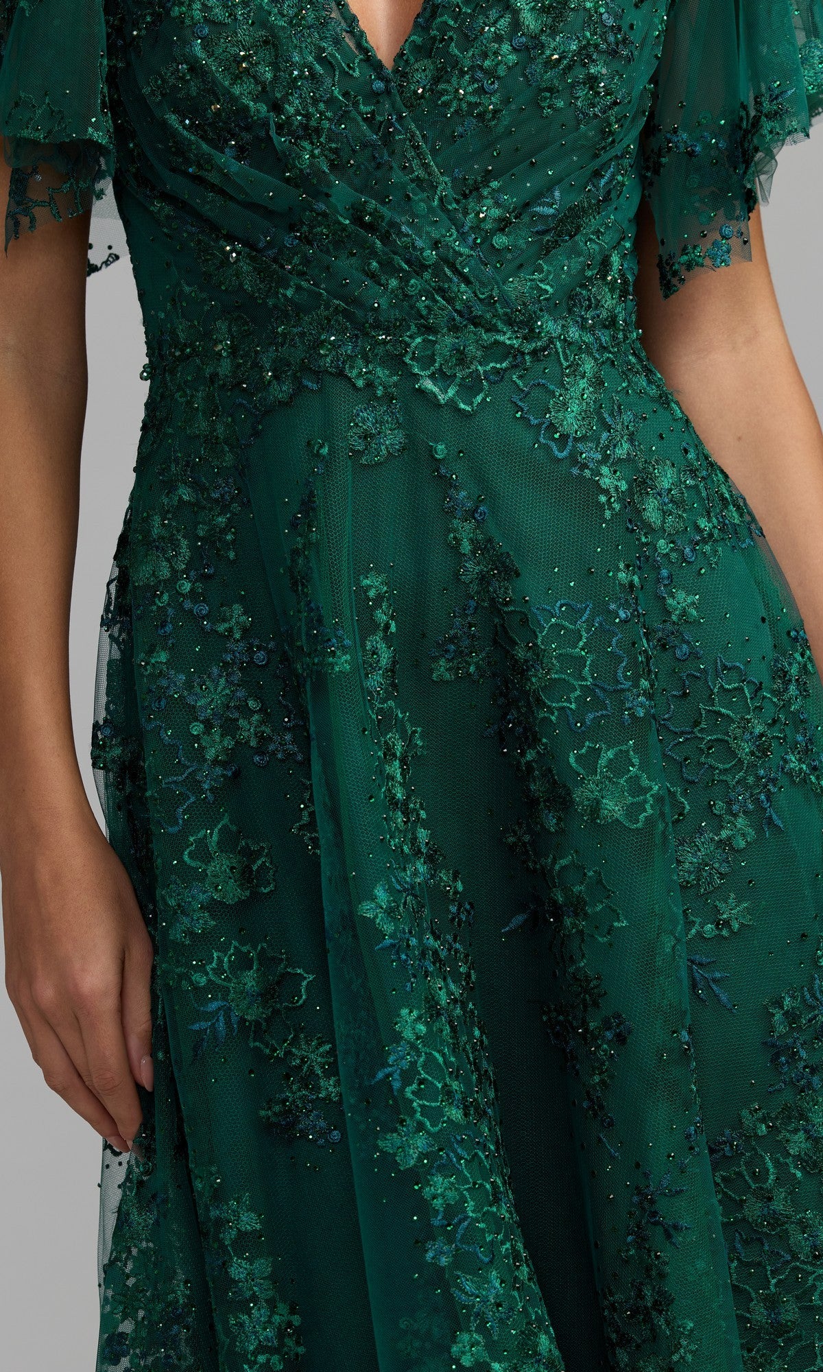 A person in a dark green floral embroidered dress stands beside the stunning Mac Duggal 20486 short sleeve mauve formal dress.
