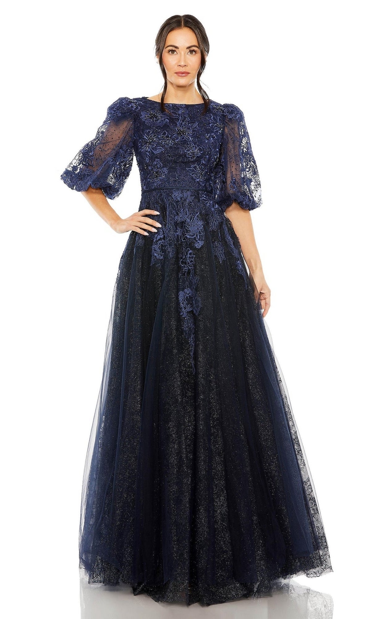 A woman wears the Long Formal Dress 20506 by Mac Duggal, a floor-length midnight blue gown with puffed short sleeves and floral detailing, standing against a white background.