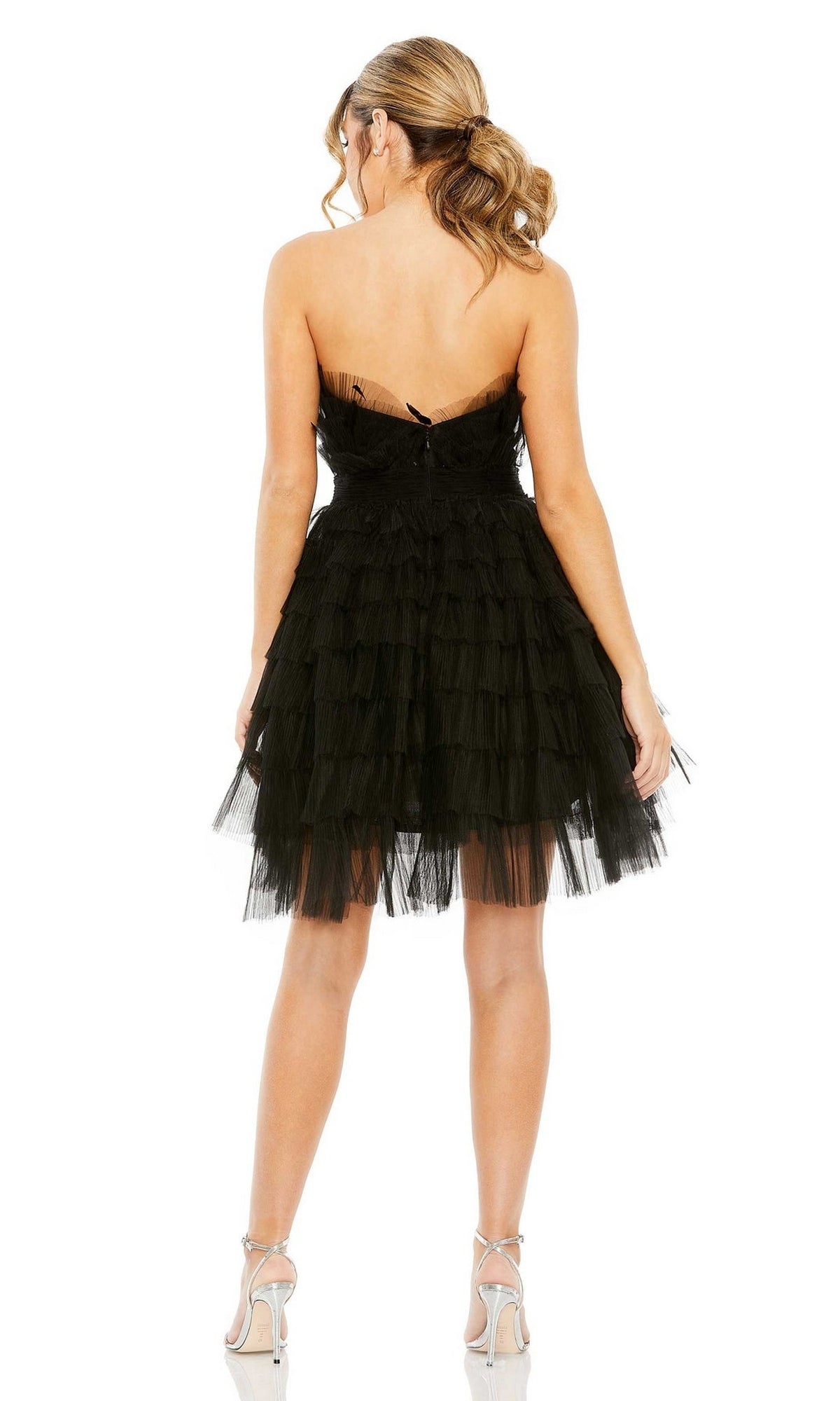A woman stands with her back to the camera, wearing the Mac Duggal 20529 Strapless Ruffle Party Dress and silver high-heeled sandals.