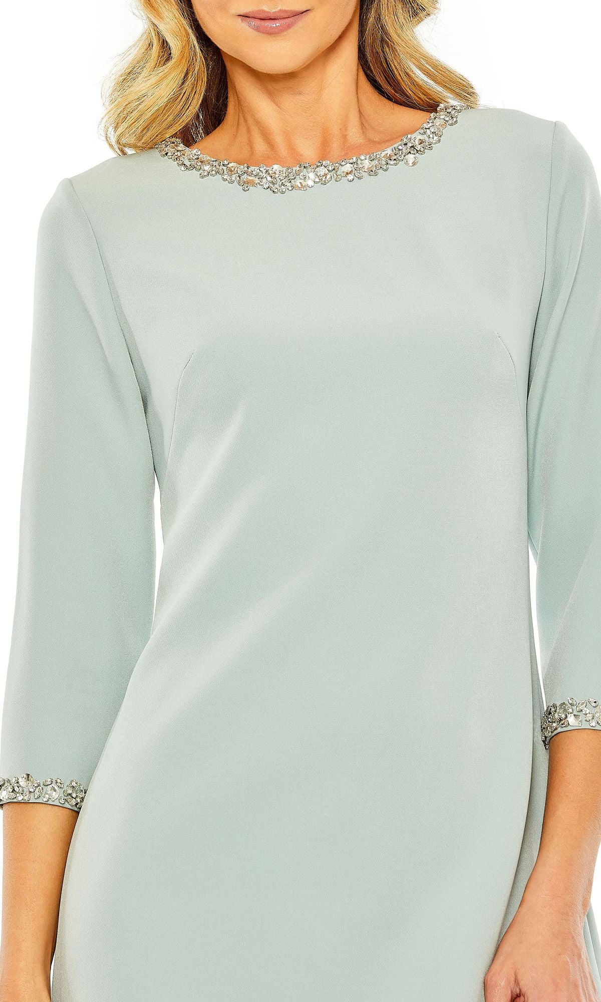 A woman wears the Mac Duggal 20697 short wedding guest dress in seafoam green, featuring three-quarter sleeves and embellished trim at the neckline and cuffs.