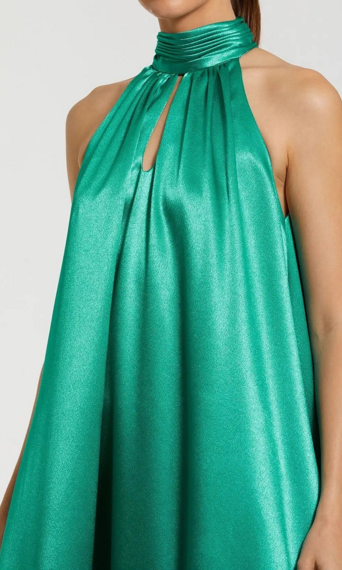 A woman wearing the Long Formal Dress: Mac Duggal 20712—a sleeveless, shiny emerald green halter-neck gown with a keyhole cutout near the collar and a high-low ruffled hem.