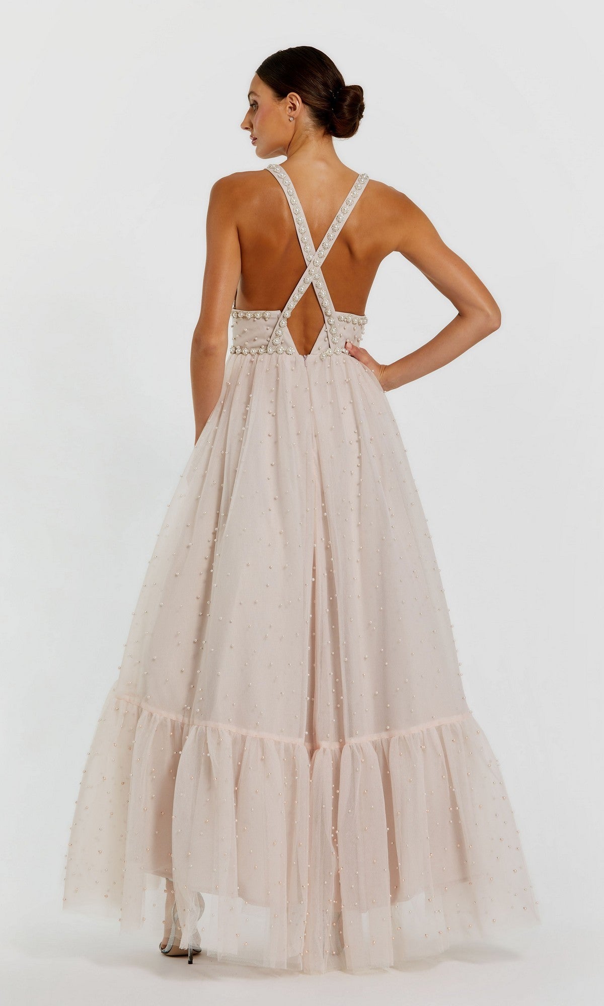 Woman in the Pearl High-Low Black Prom Dress by Mac Duggal 20747, featuring a high-low hem, pearl accents, and elegant detailing, poses with one hand on her hip.