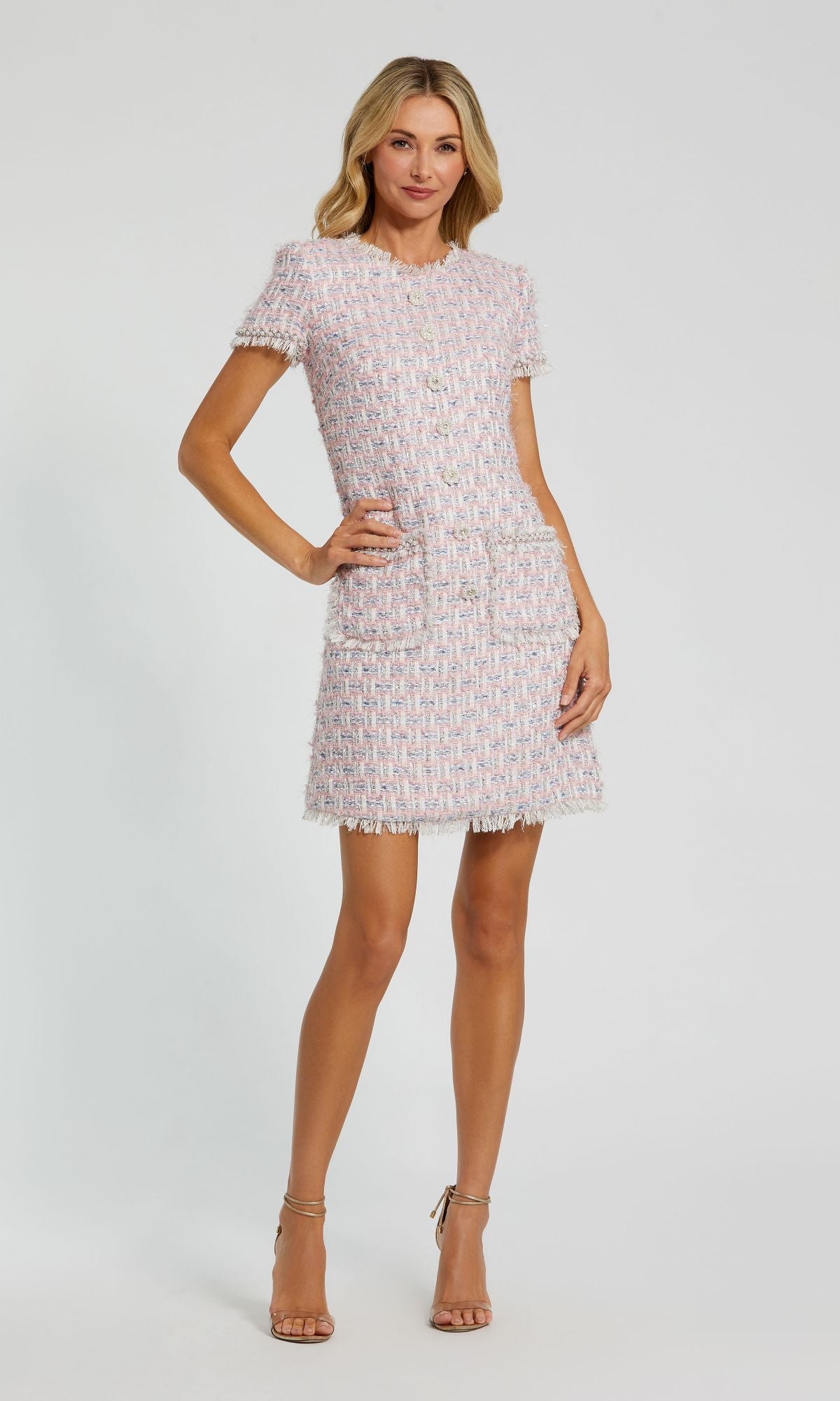 A woman wears the Mac Duggal 20805 short sleeve semi-formal dress with front pockets and gold buttons, paired with nude high heels. The scene is set against a plain white background.