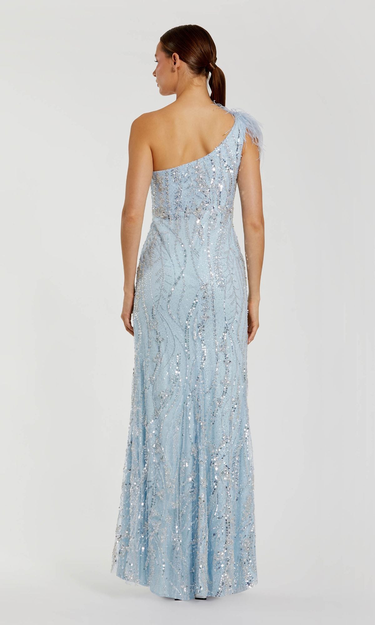 A woman stands facing away from the camera against a plain background, wearing the Mac Duggal 20887 long blue glitter formal dress.