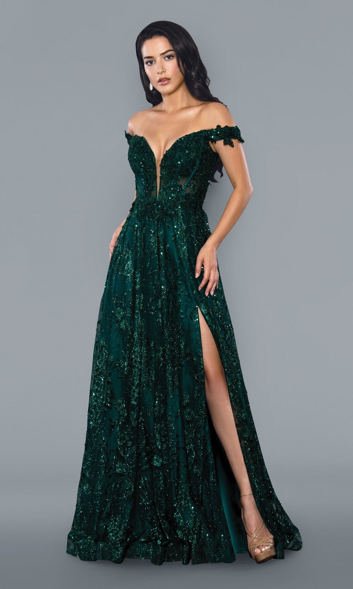 A woman poses against a plain gray background, wearing the Stella Couture 21064 long prom dress in green, featuring an off-the-shoulder design, floor-length A-line silhouette, and a thigh-high slit.
