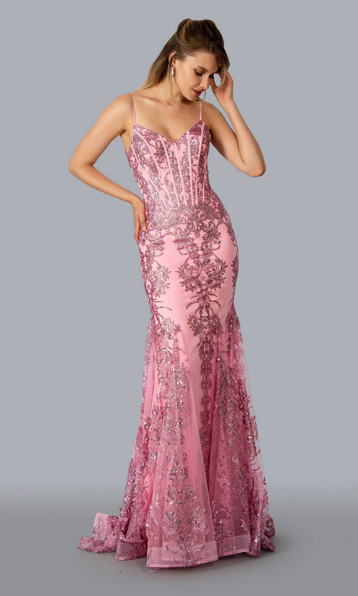 A woman stands against a plain gray background wearing the Corset-Bodice Sparkly Long Mermaid Prom Dress 21066, featuring a fitted silhouette, floor-length design, thin straps, and intricate silver embroidery.