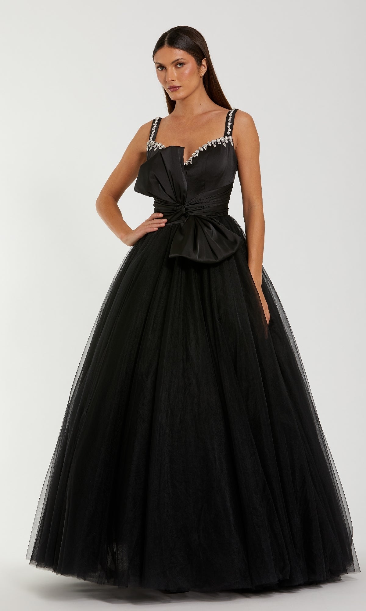 Woman modeling a black ball gown standing in front of a white background