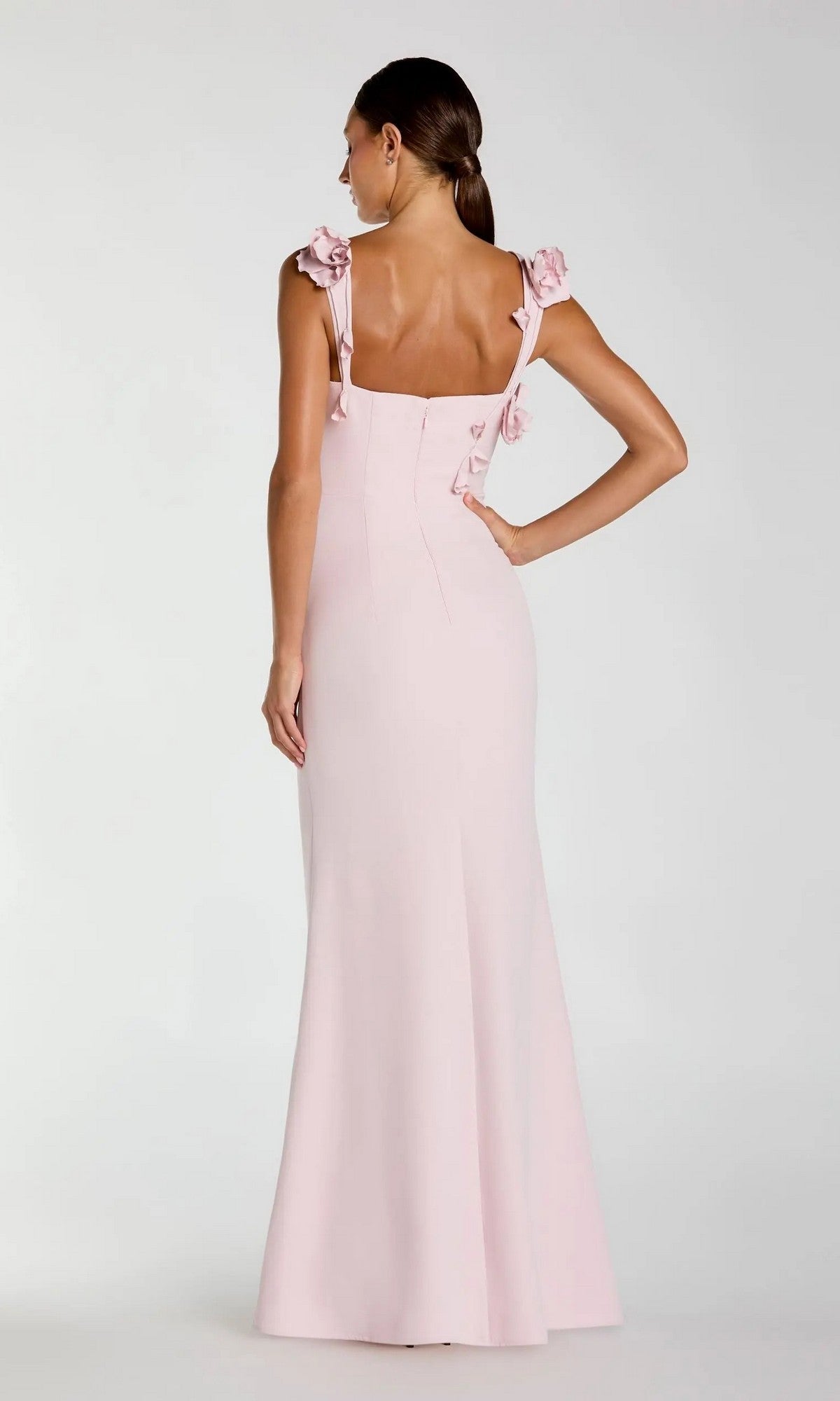 A woman stands with her back to the camera against a plain white background, wearing the Mac Duggal 21236 long formal dress in light pink, featuring floor-length design and ruffle details on the shoulder straps and cascading down the back.