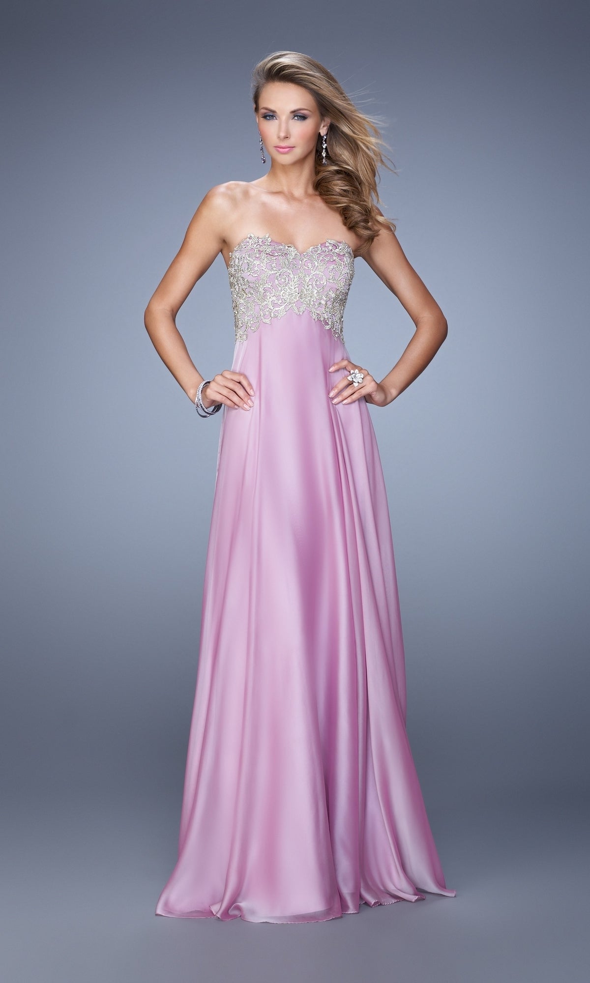 A woman stands against a grey background wearing the La Femme Embroidered Chiffon Prom Dress 21289, featuring a strapless design and a beaded, embroidered bodice.