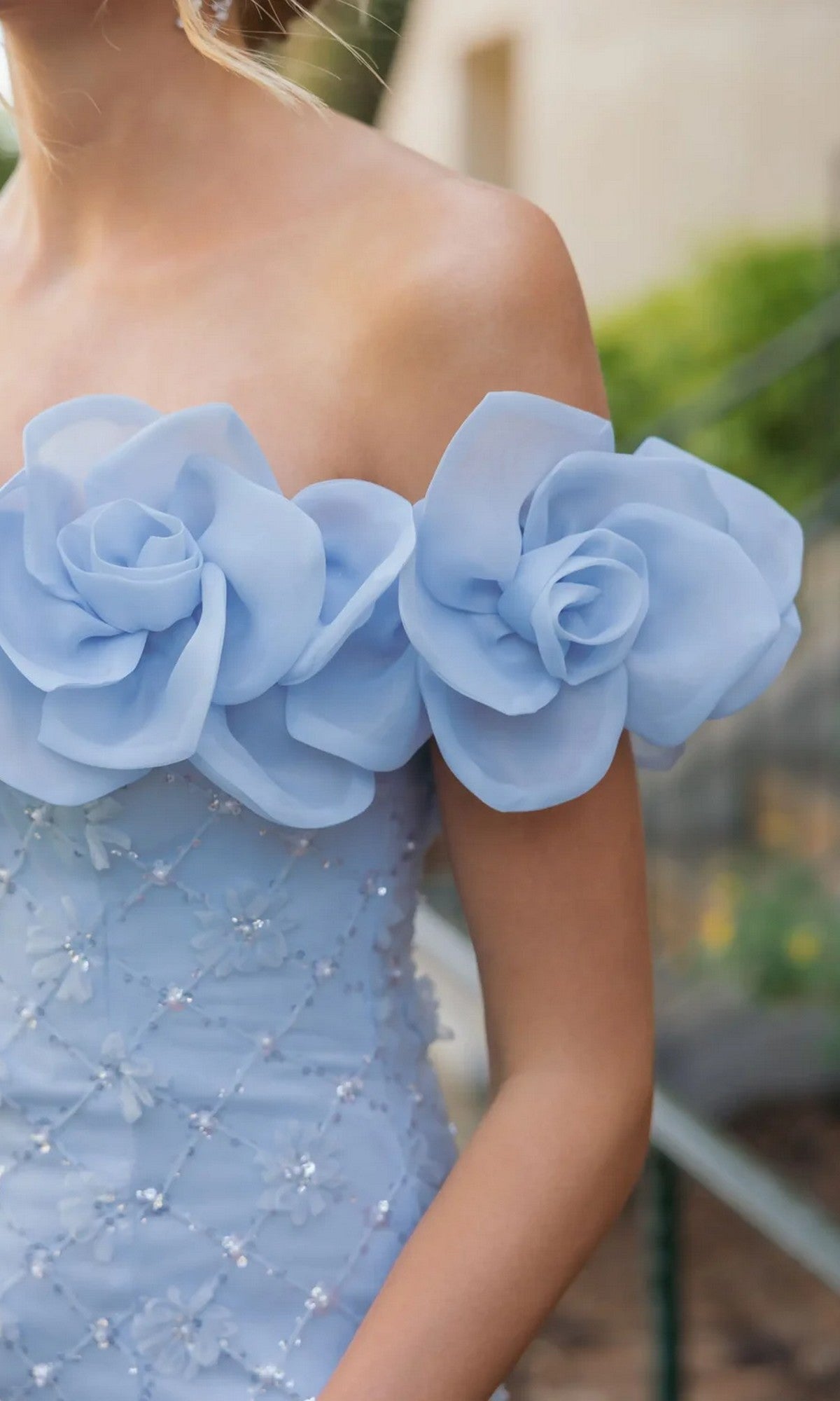 Wearing the Mac Duggal 21363 midi party dress in light blue, featuring an off-the-shoulder neckline, large fabric flower accents, and delicate beading.