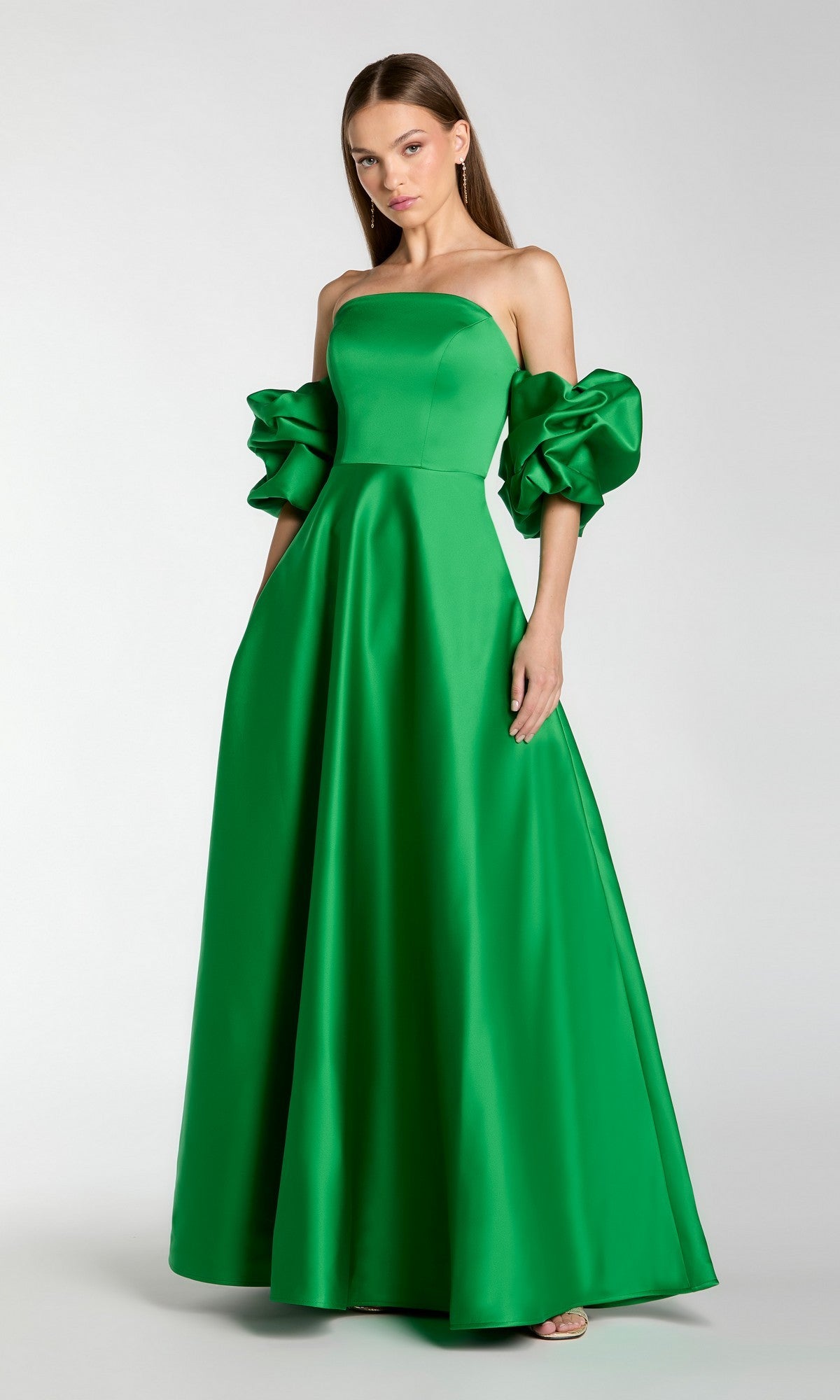 A woman wearing the Mac Duggal 21375 long formal dress in spring green—with a strapless neckline and voluminous off-the-shoulder puff sleeves—stands against a plain light background.