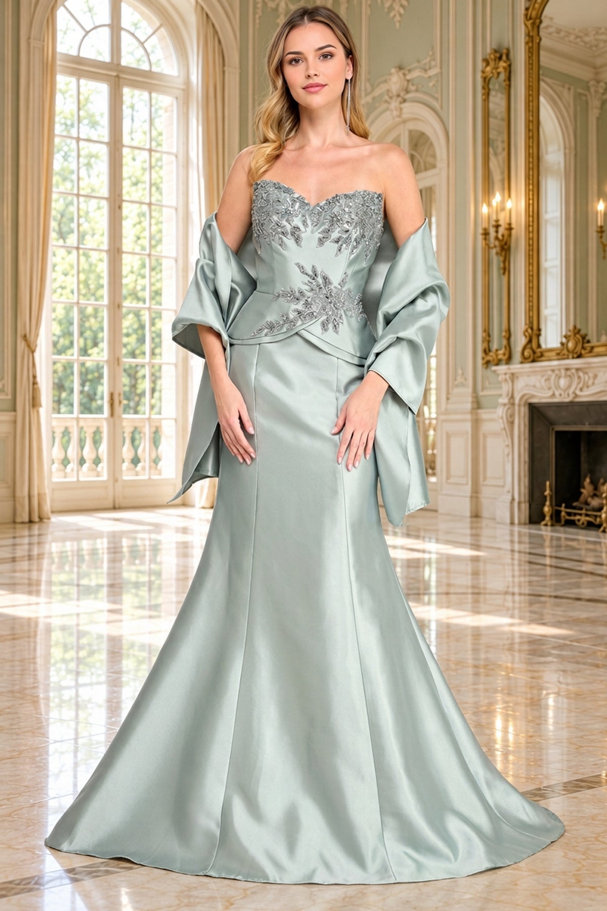 A woman wears the light green Long Formal Dress: Amelia Couture 2162, featuring a strapless bodice with silver floral embroidery and a matching shawl draped over her arms.