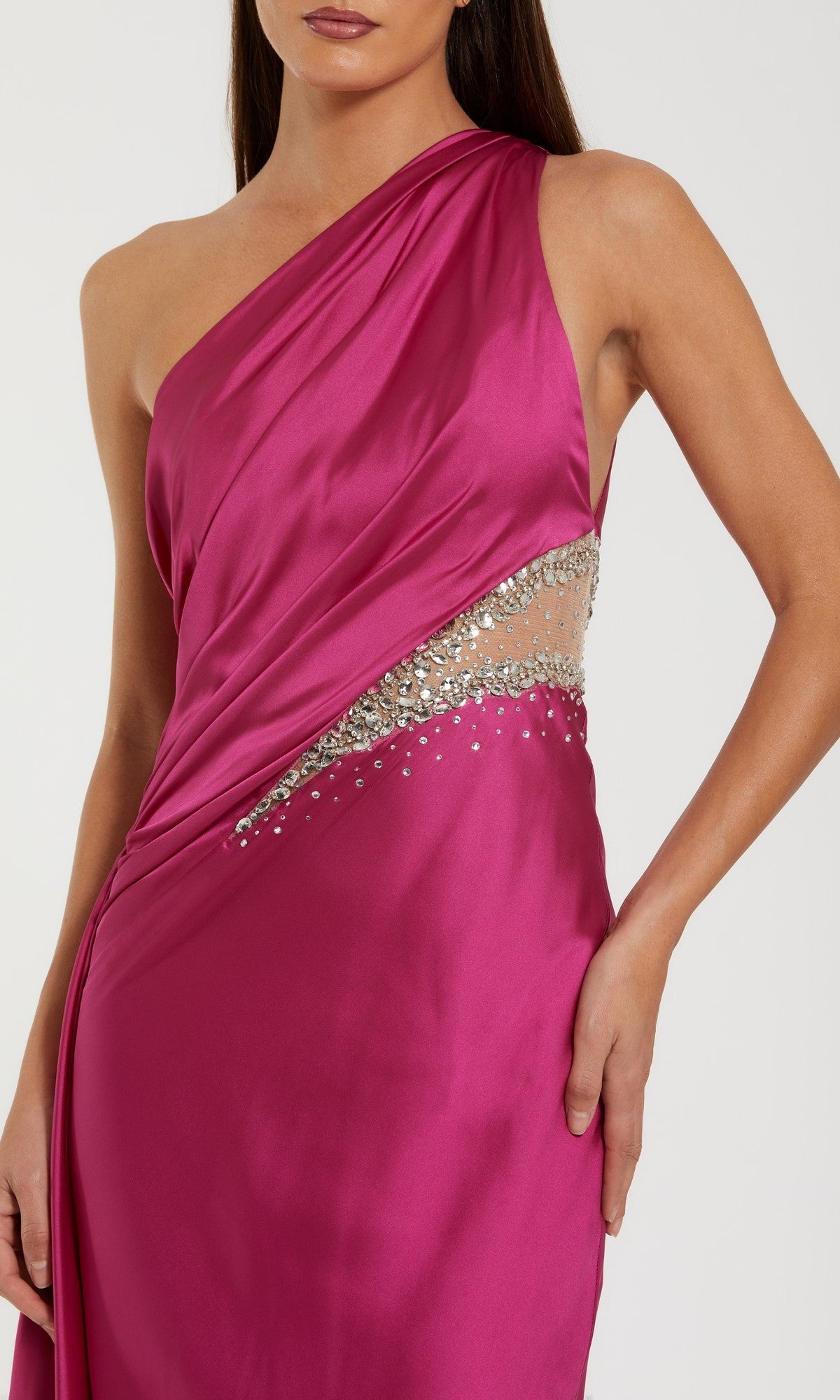 A woman wears the Mac Duggal 2210 Cut-Out One-Shoulder Formal Dress—magenta, with a sheer waist cut-out and silver rhinestone embellishments.