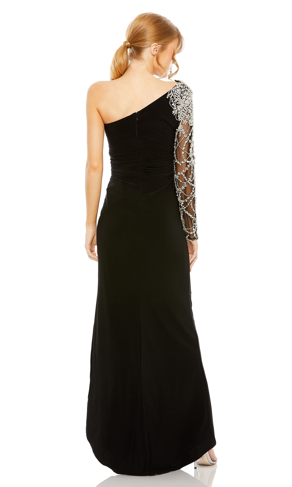 A woman stands with her back to the camera wearing the Long Formal Dress 2215 by Mac Duggal, a fitted black one-shoulder gown featuring an embellished sheer long sleeve.