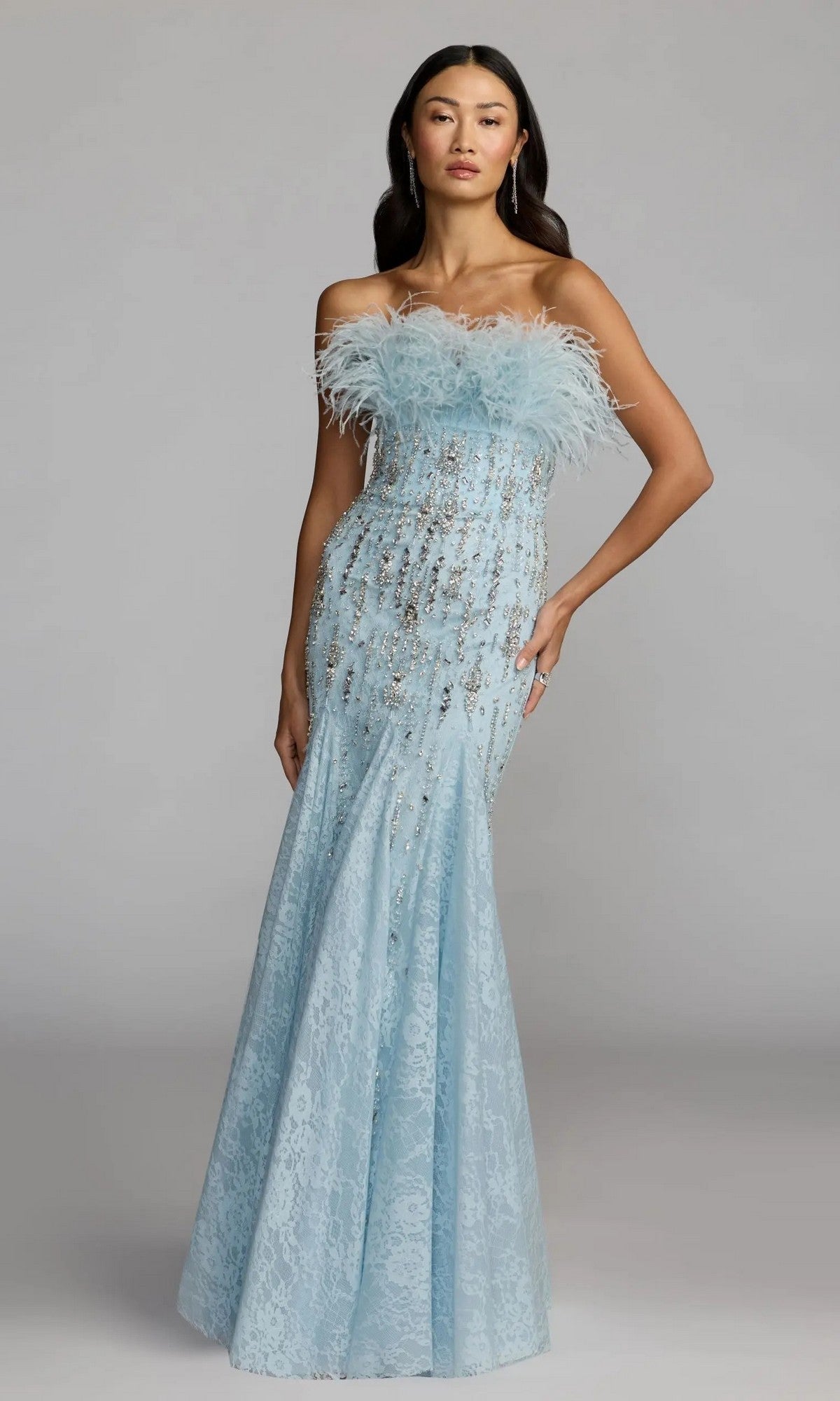 A woman wears the Mac Duggal 2238 long formal dress—a powder blue, strapless mermaid gown with lace, feather-embellished neckline, and sparkling accents—standing against a plain background.