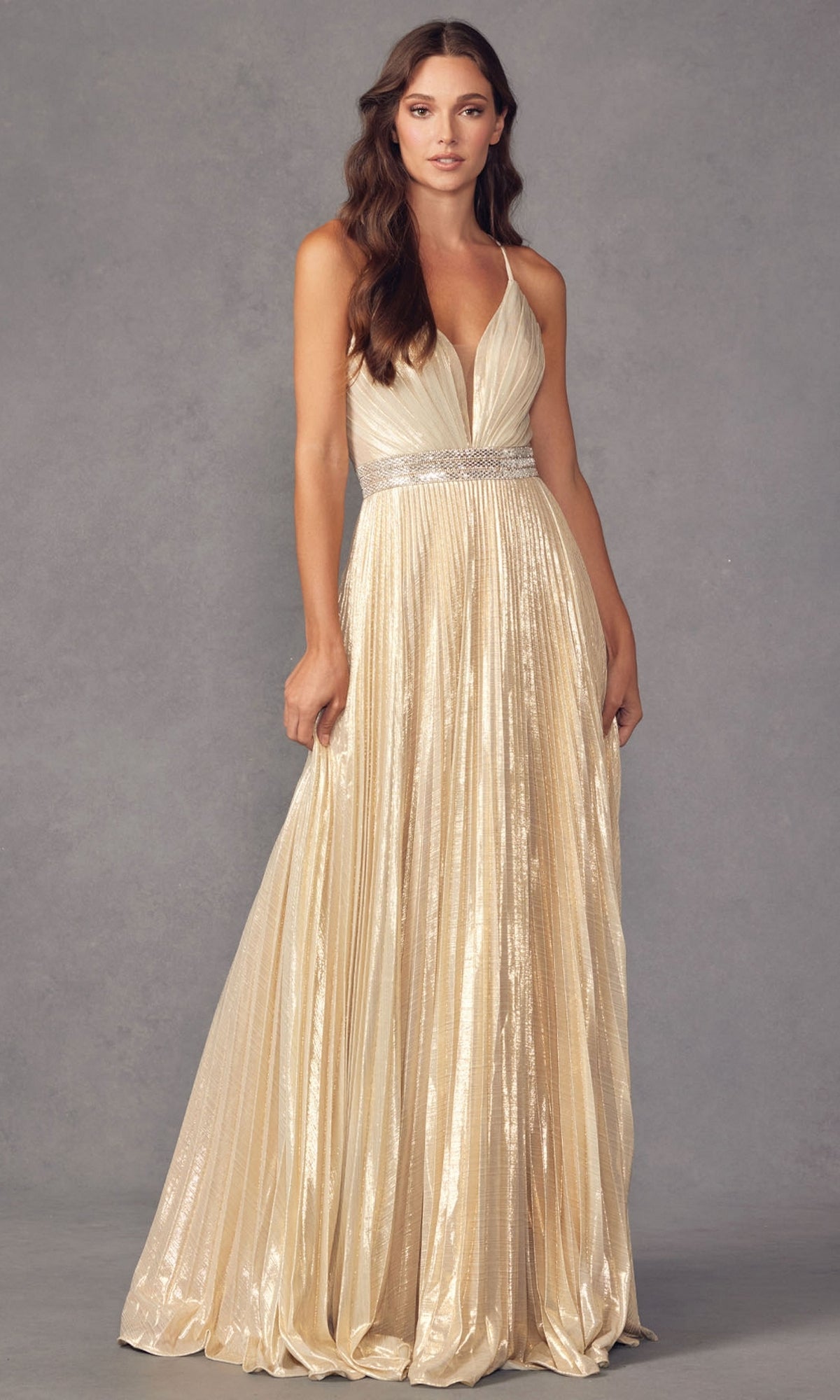 A woman wears the Deep V-Neck Pleated Long A-Line Prom Dress 226, featuring a floor-length pleated skirt and sparkly rhinestone belt, against a neutral gray background.