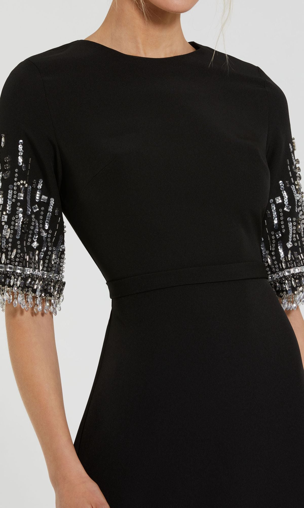 A woman wears the Mac Duggal 2270 Short Sleeve Sleek Formal Dress, a long black gown adorned with silver and clear bead detailing.
