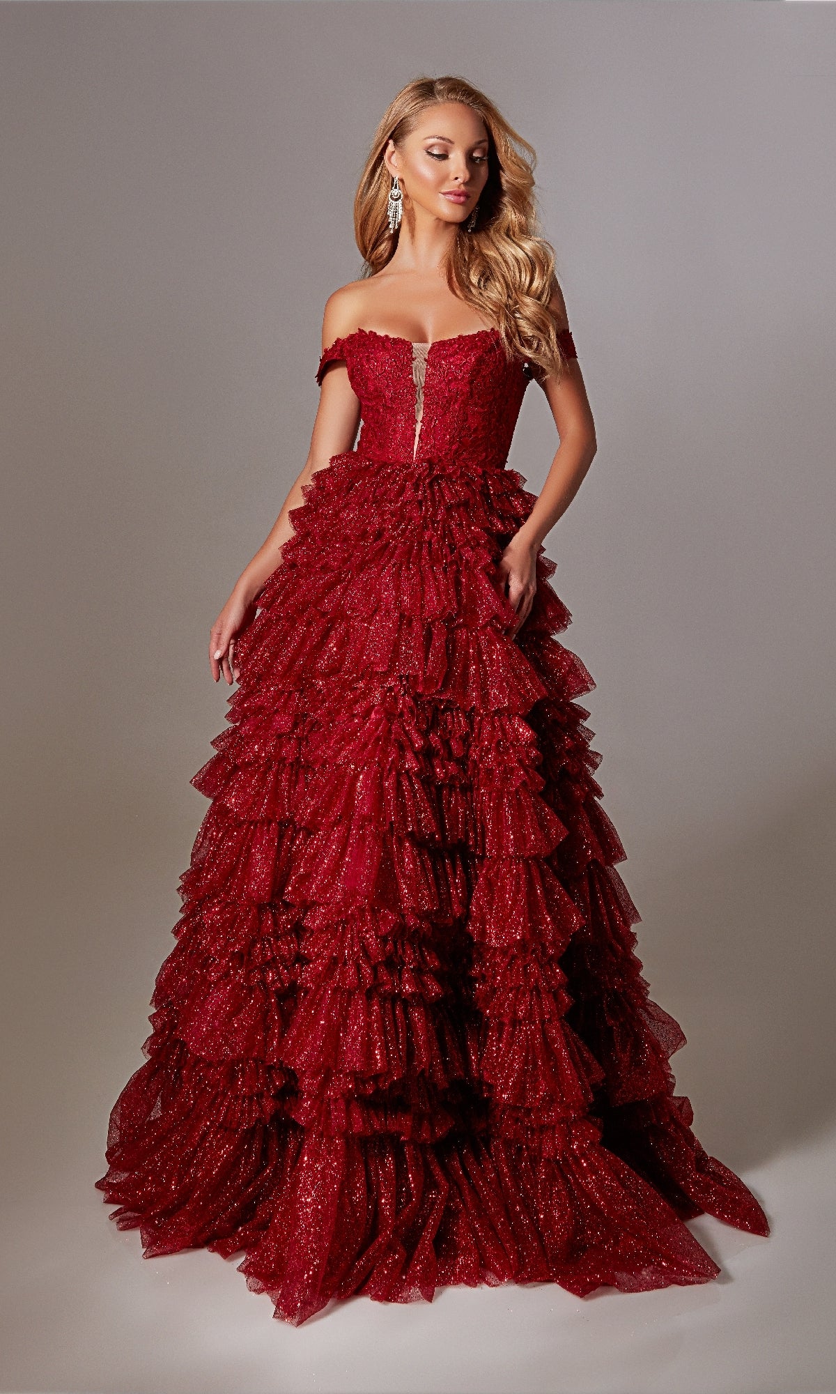 A woman wears a glamorous Lace-Up Long A-Line Glitter Prom Dress with ruffles, posing against a plain background.