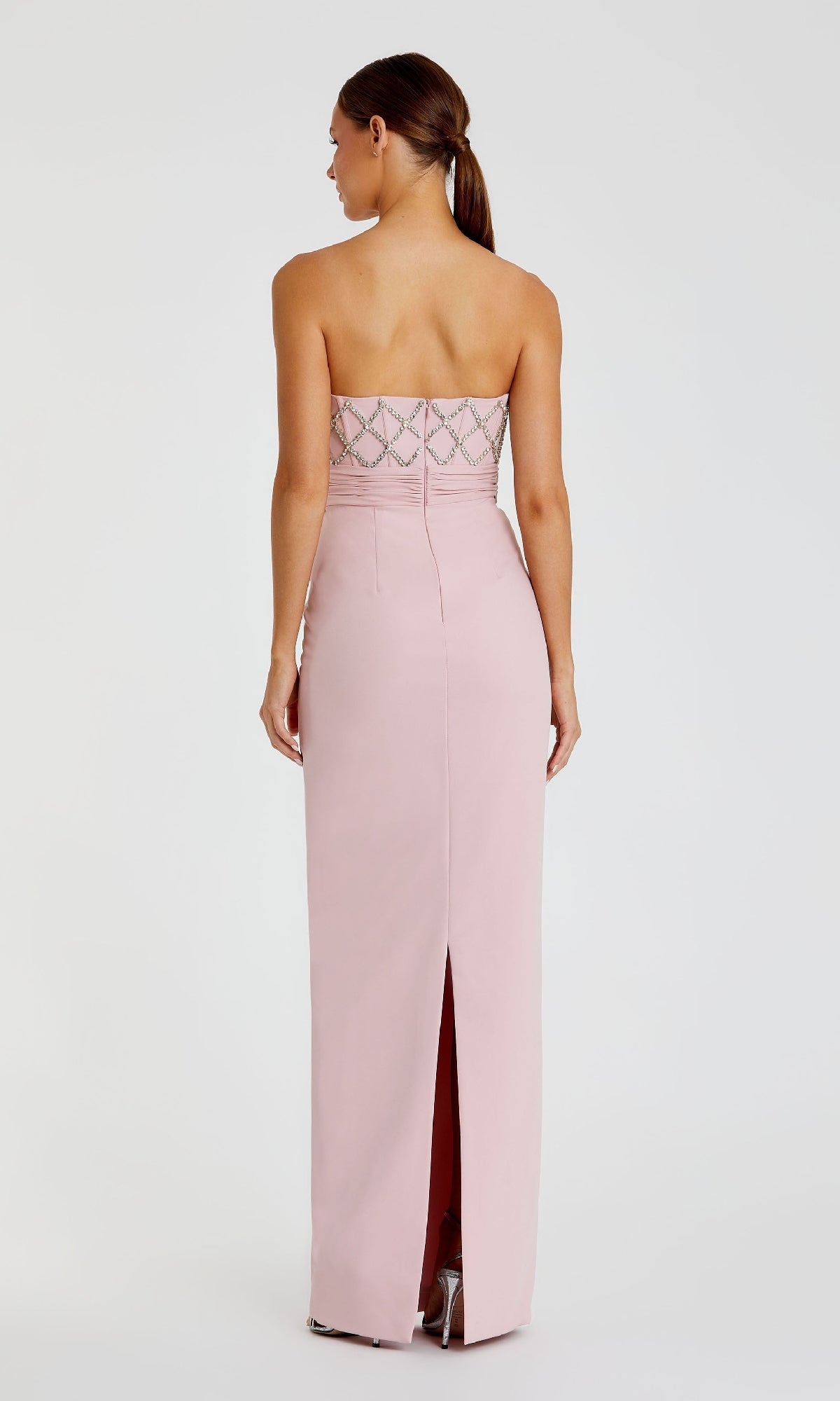 A woman faces away wearing the Strapless Sweetheart Formal Gown: Mac Duggal 2294—a light pink, beaded-bodice dress with a back slit—posing elegantly against a plain white background.