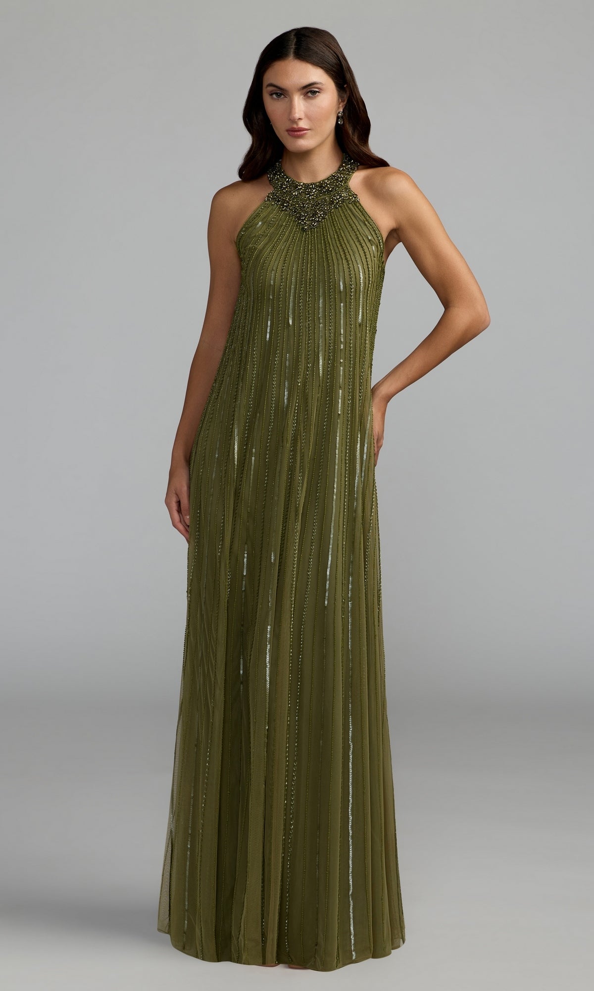 A woman wearing the Mac Duggal 23043 long formal dress in olive, featuring a sleeveless design and beaded halter neckline, stands against a plain gray background.