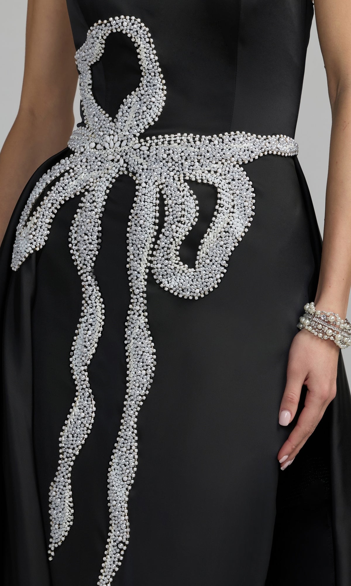 A woman wearing a strapless long blue formal dress (Mac Duggal 2317) with matching beaded bracelets on her wrist.