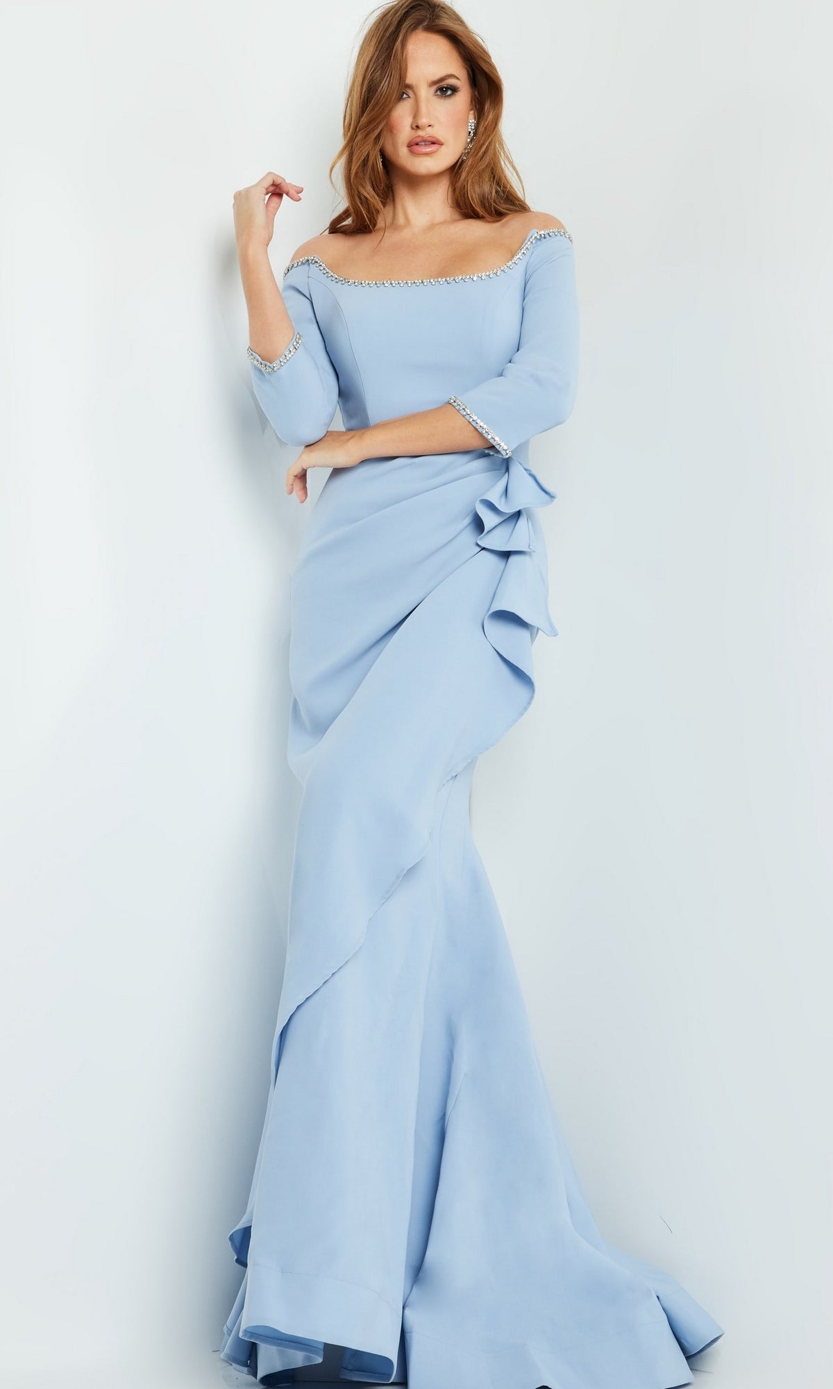 Woman wearing the Jovani Long Formal Dress with Bead Trim 23190, an off-the-shoulder light blue gown featuring ruffle details and sparkling beaded trim, posing against a white background.