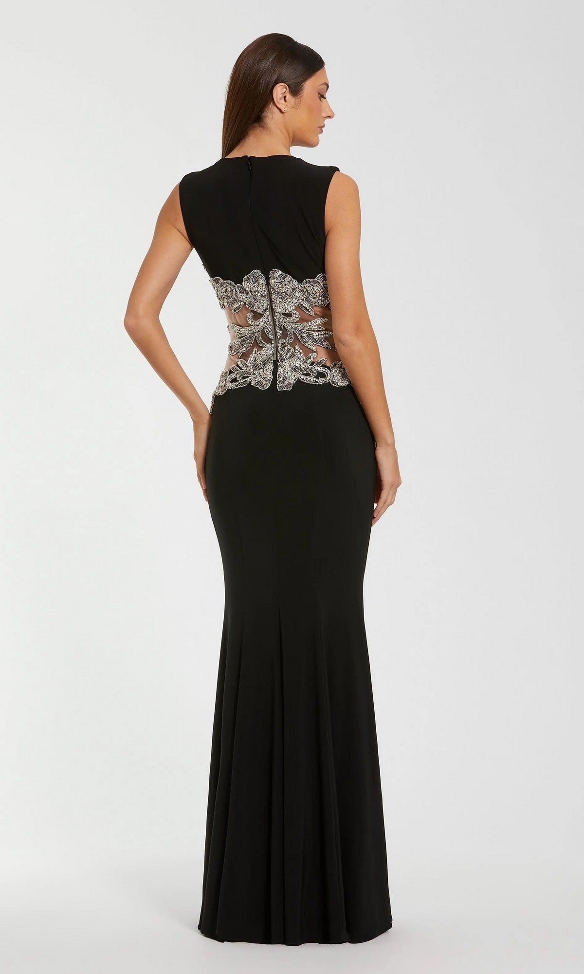A woman models the Long Formal Dress: Mac Duggal 2324, a floor-length black gown with silver lace detailing on the back and a beaded illusion waist, set against a plain, light background.
