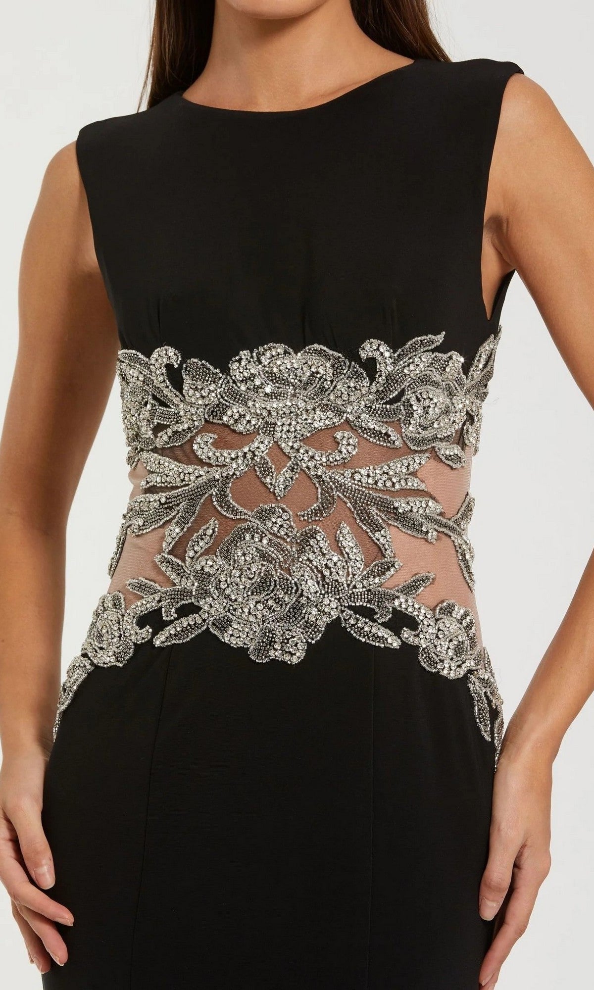 Woman in the Mac Duggal 2324 long formal dress, a sleeveless black designer gown with a beaded illusion waist, sheer panels, and intricate silver sequin and bead floral embellishments.
