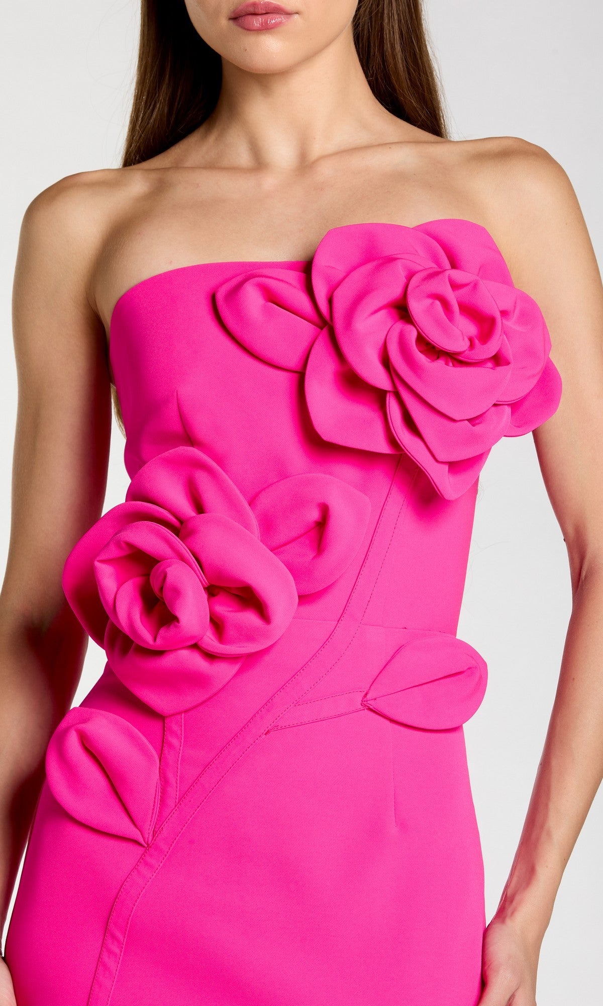 A woman wearing the Mac Duggal 2361 long formal dress in bright pink, featuring a strapless crepe midi silhouette with dramatic 3D floral appliques on the bodice and hip.