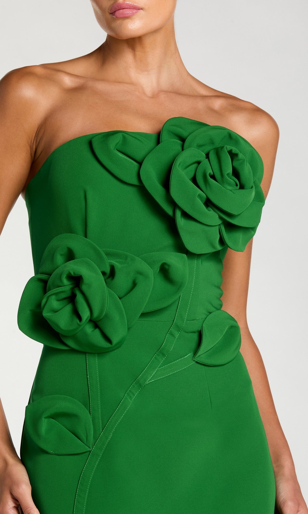 A woman wearing the Mac Duggal 2361 long formal dress, a strapless green crepe design featuring a fitted bodice and adorned with large fabric roses, leaves, and intricate 3D floral appliques across the chest and waist.