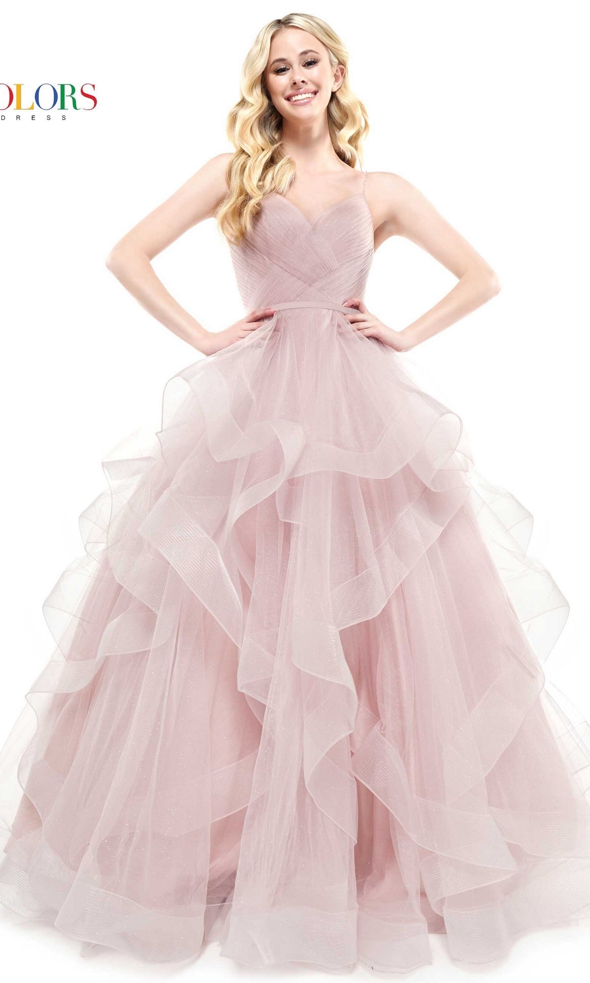 A woman stands with her hands on her hips, smiling at the camera in the Layered Long Tulle Prom Ball Gown 2381—a light pink, strapless formal dress featuring ruffles and an a-line tulle skirt.