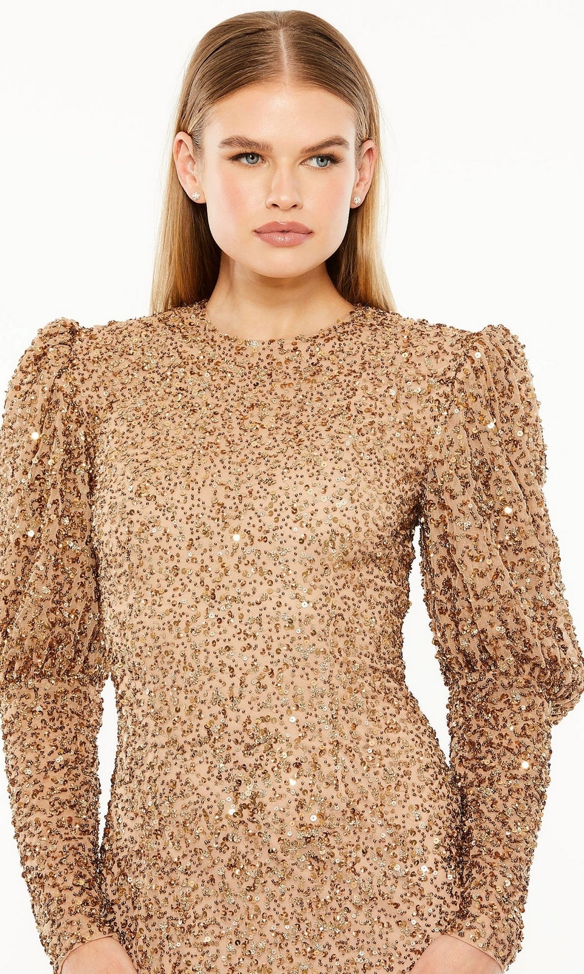 A woman models the Long Formal Dress 24000 by Mac Duggal, featuring shimmering gold sequins, puffed shoulders, and long sleeves, set against a white background.