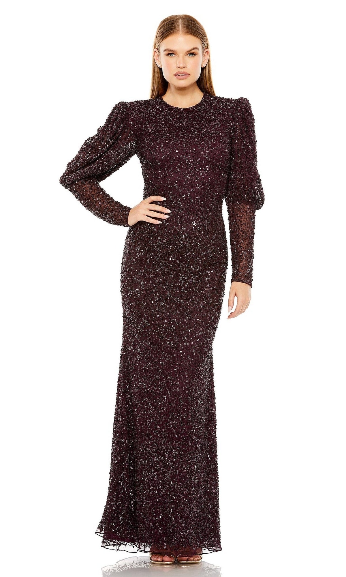 A woman stands facing forward in a long-sleeved, floor-length Long Formal Dress 24000 by Mac Duggal featuring sequins, a fitted waist, and slightly puffed shoulders.