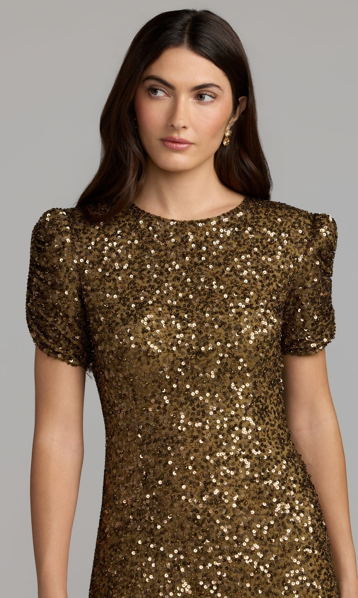A woman wears the Mac Duggal 24003 Short Sleeve Sequin Formal Dress in gold, featuring short puff sleeves, as she stands against a plain light gray background.