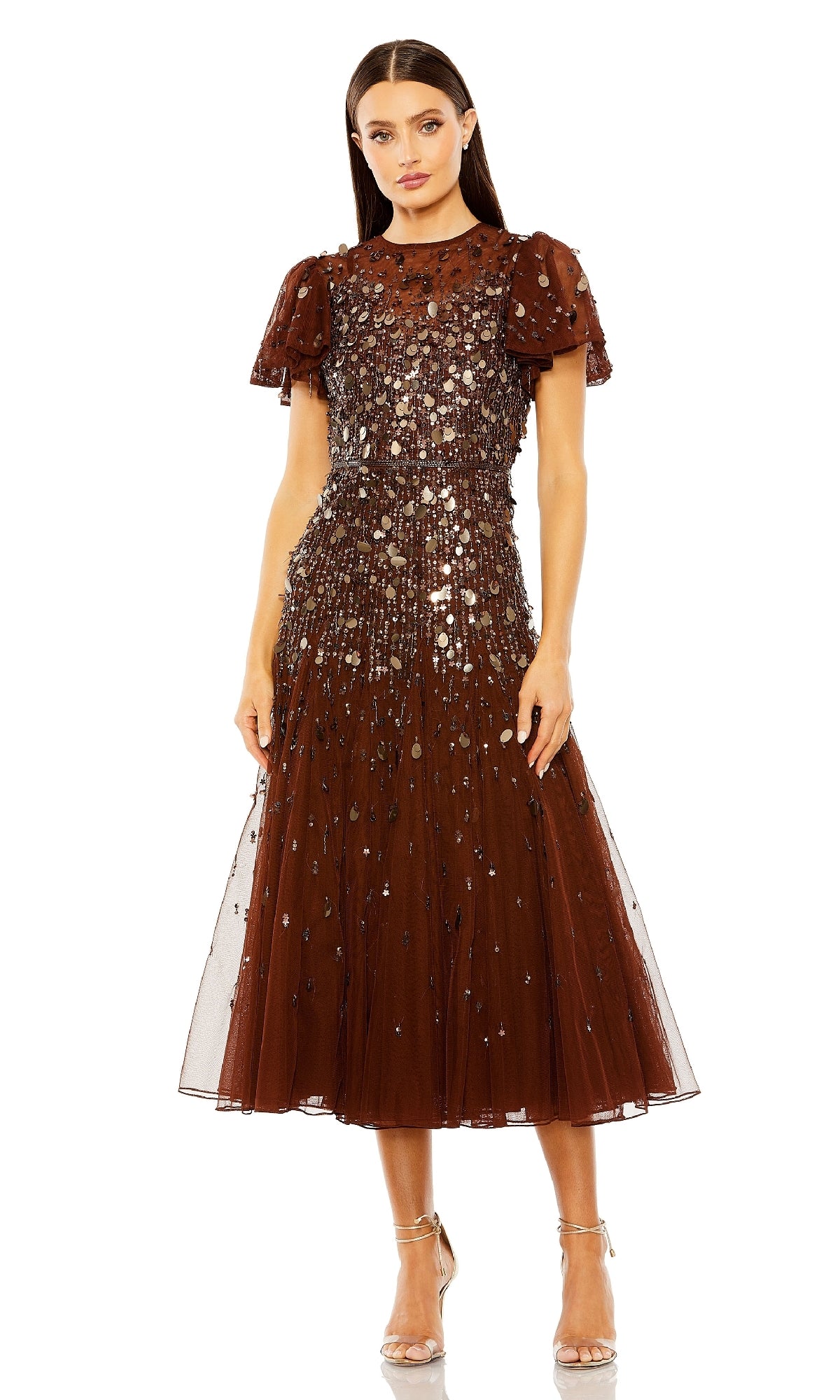 A woman wears the Mac Duggal 24018 brown tea-length party dress with sequin embellishments and strappy nude heels, standing against a white background.
