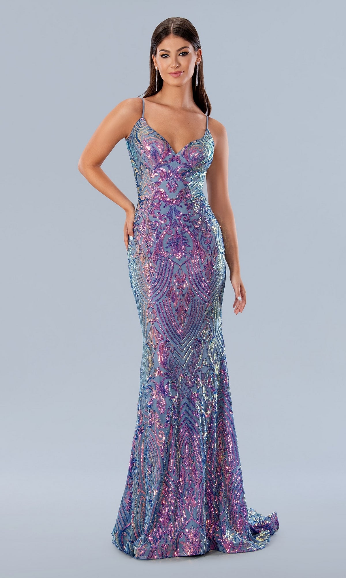 A woman poses against a plain gray background wearing the Long Prom Dress 24160 by Stella Couture, a fitted, floor-length purple sequin mermaid dress featuring blue and pink patterns and an elegant v-neckline.