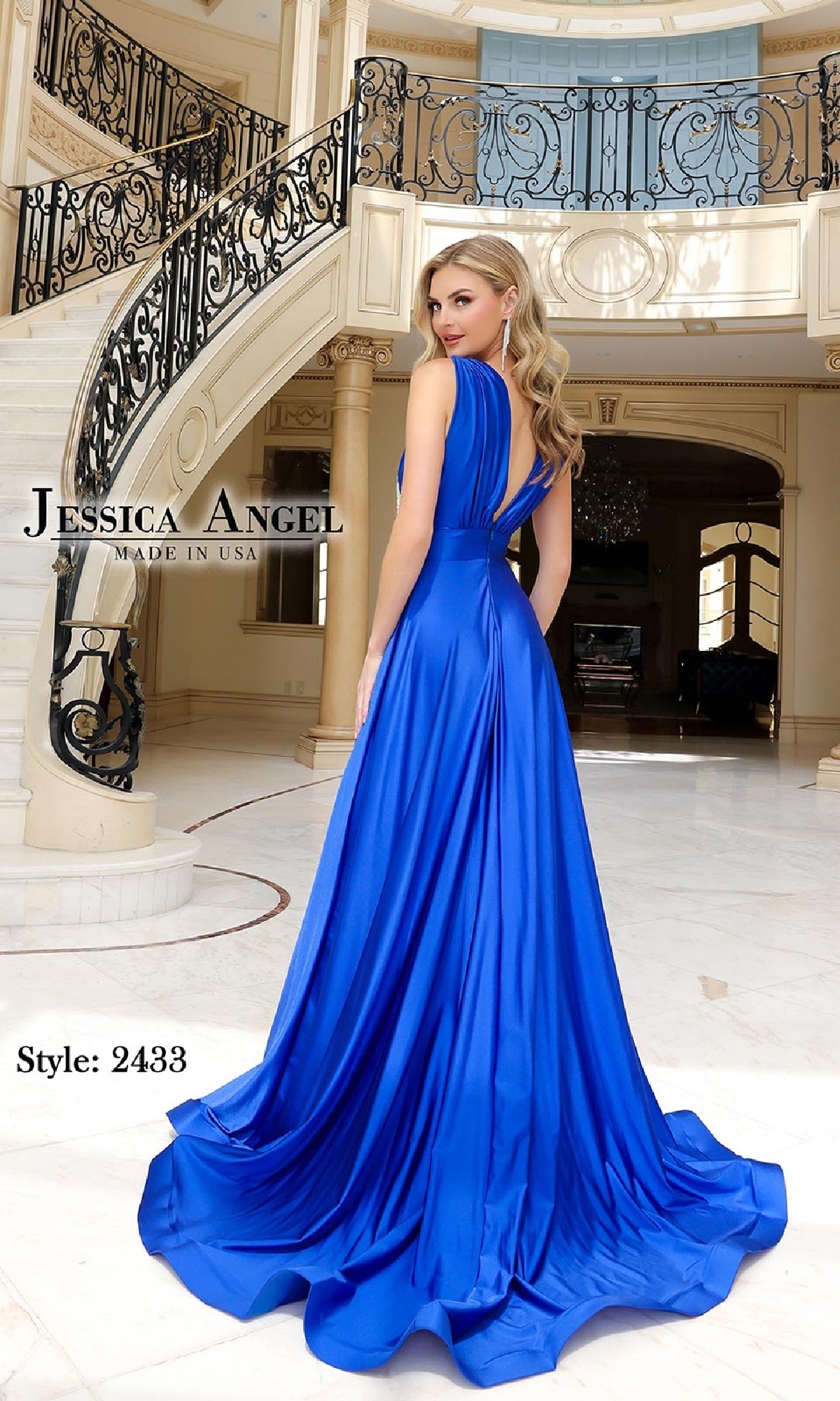 A woman models the Jessica Angel 2433 Deep V-Neck Long Prom Dress in an elegant foyer with marble floors, a curved staircase, and an ornate railing in the background.