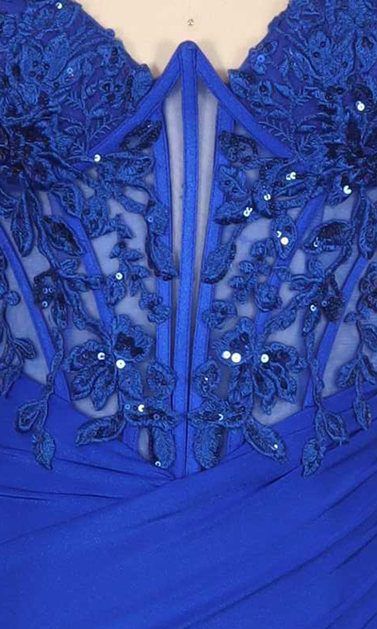 Close-up of a royal blue dress with intricate floral lace embroidery on a sheer corset bodice.