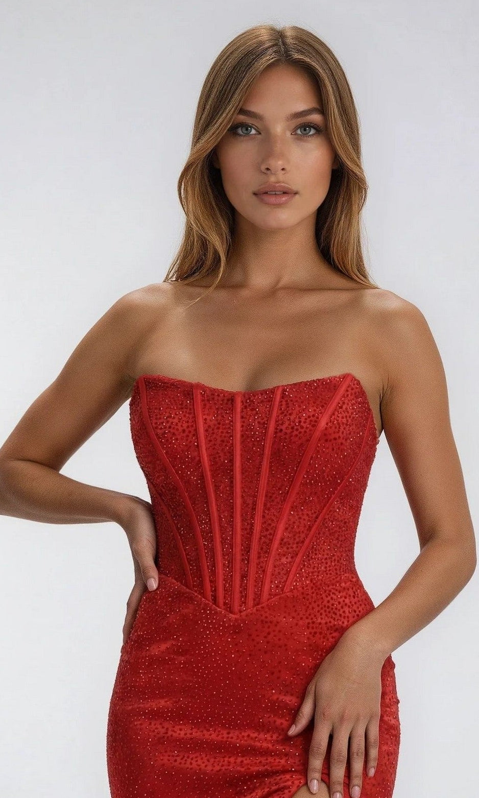 A woman in the PromGirl Exclusive 250207, a strapless long prom dress with a daring leg slit and sparkling heat stone embellishments.