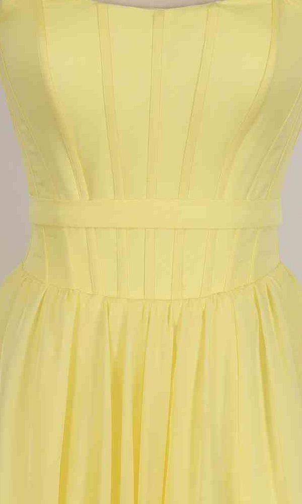 Close-up of the Long Prom Dress: PromGirl Exclusive 250236B featuring a sleeveless yellow design, vertical seams on the corset bodice, a fitted waistband, and a flowing A-line skirt.