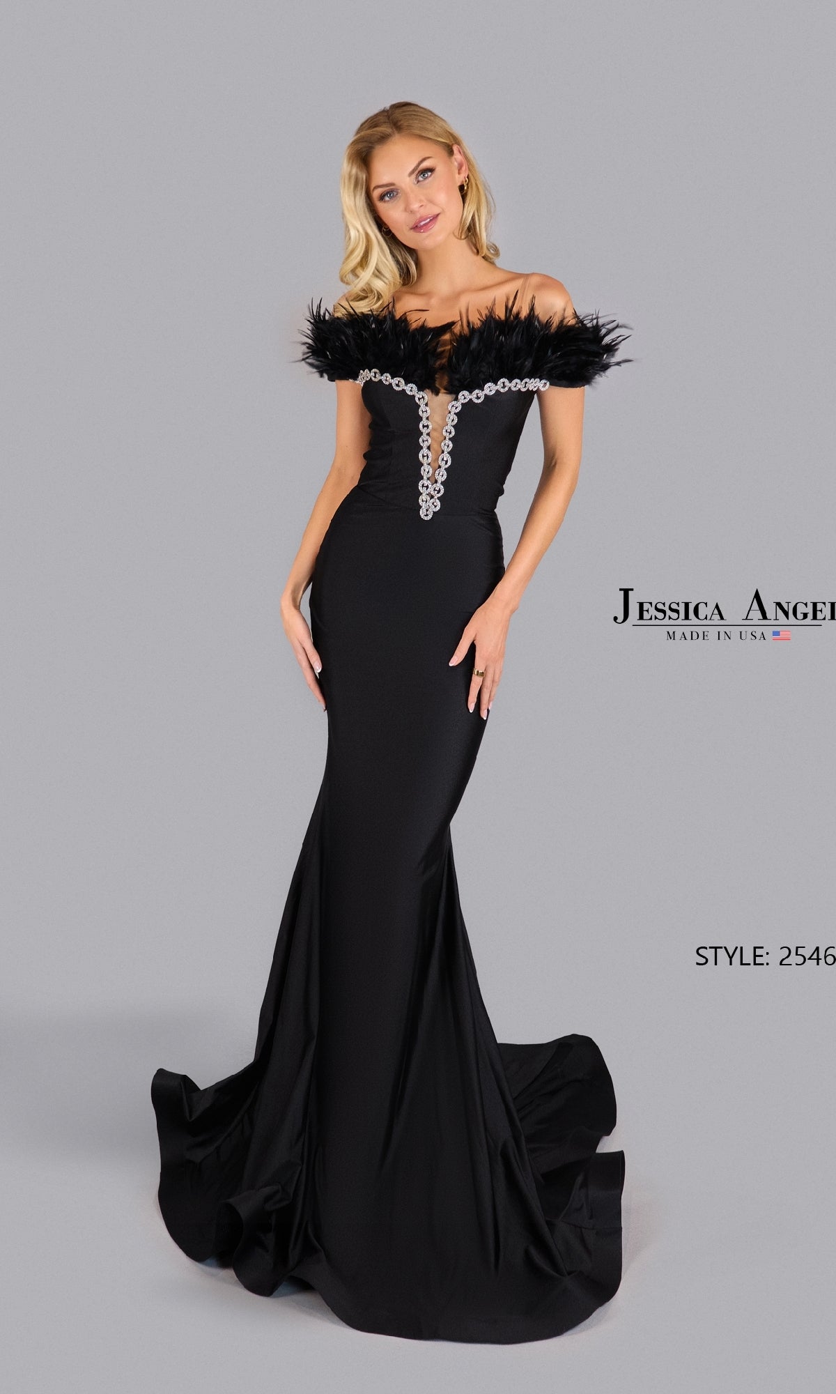 A woman models the Jessica Angel 2546, a floor-length black prom dress with off-the-shoulder feather details and jeweled bodice, standing before a plain gray background.